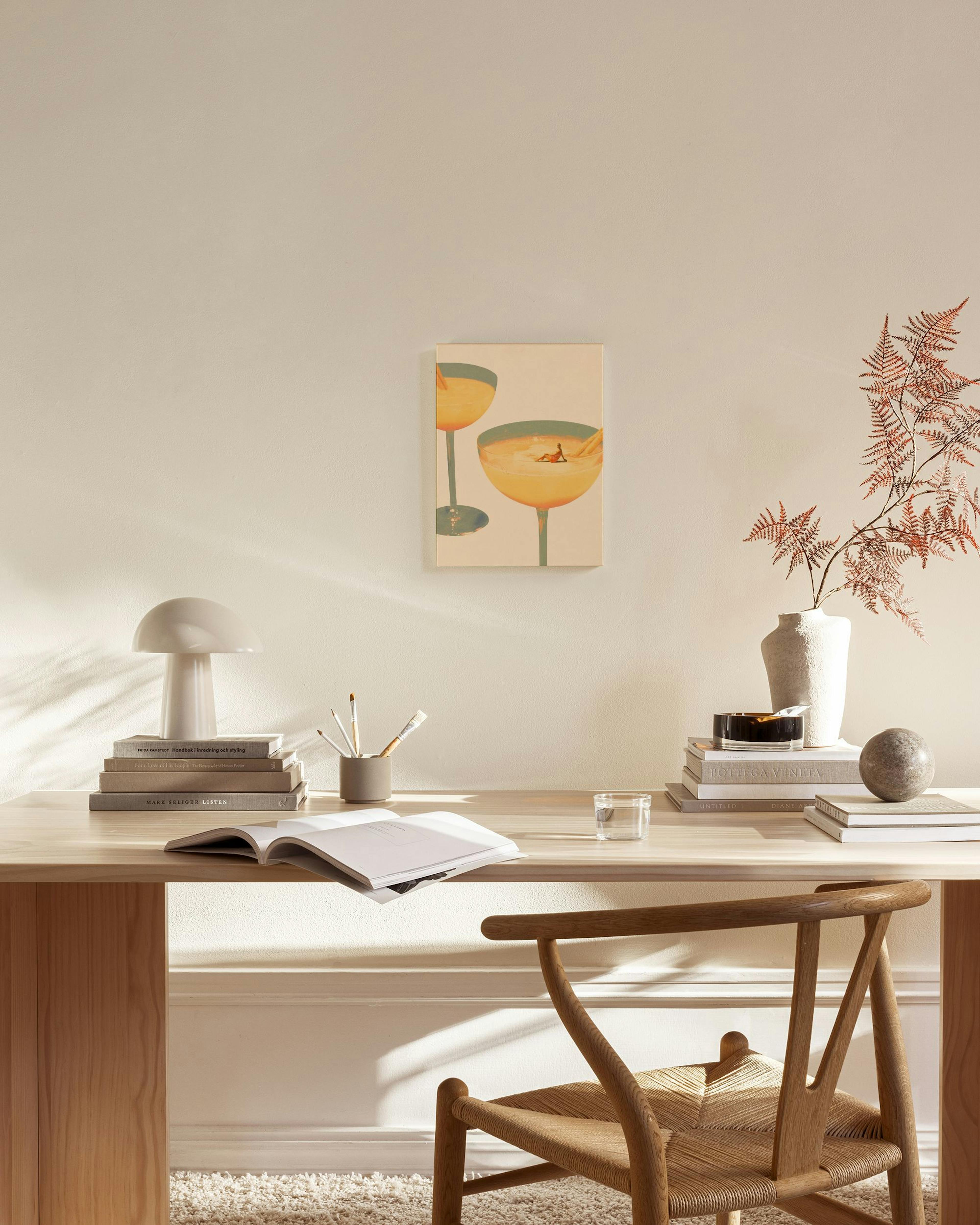 Toile dune femme bronzant dans un verre à cocktail rempli dune boisson jaune, avec un autre verre en arrière-plan.