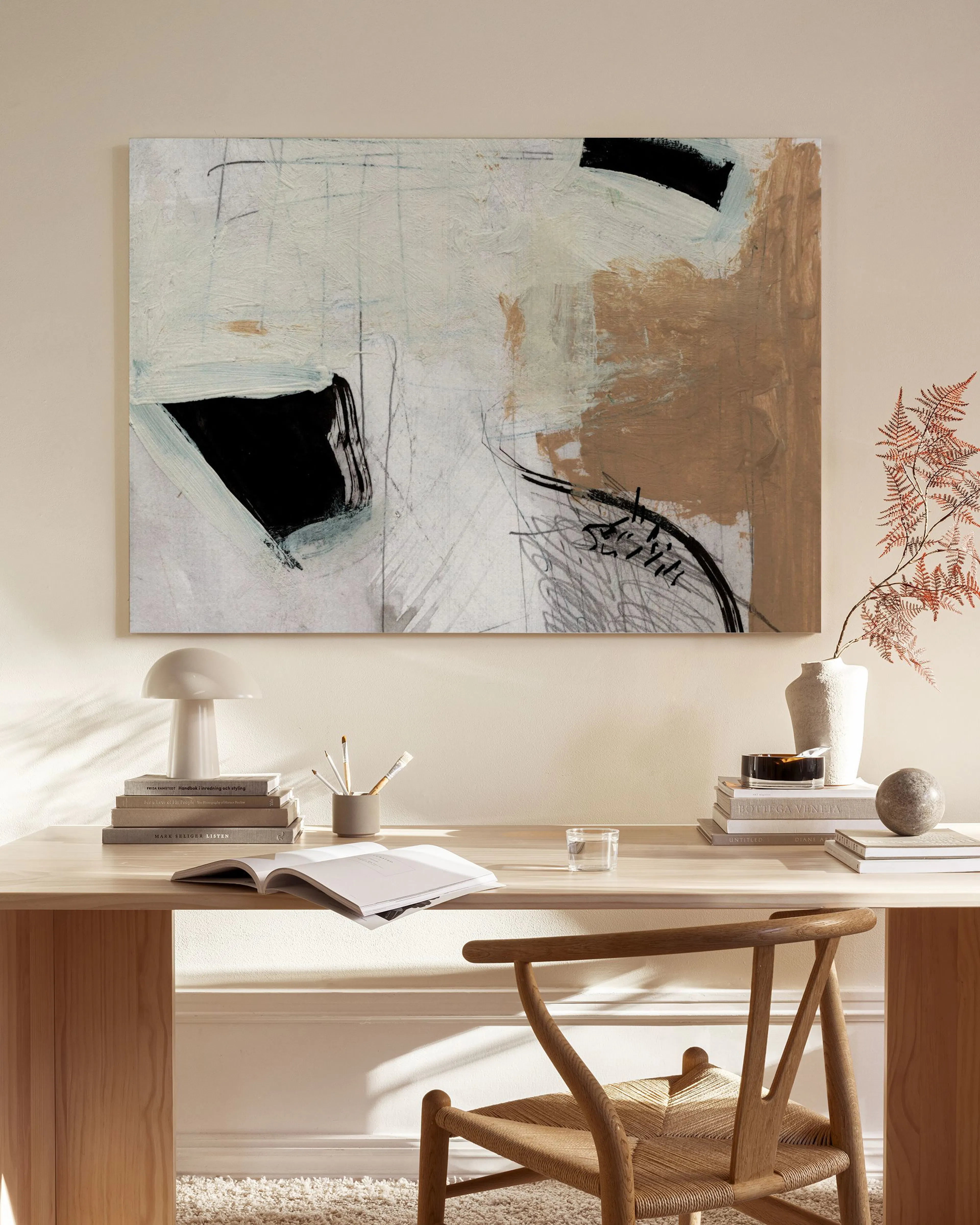 Toile abstraite avec formes noires, beiges et blanches, suspendue dans un salon moderne au-dessus dun banc en bois.