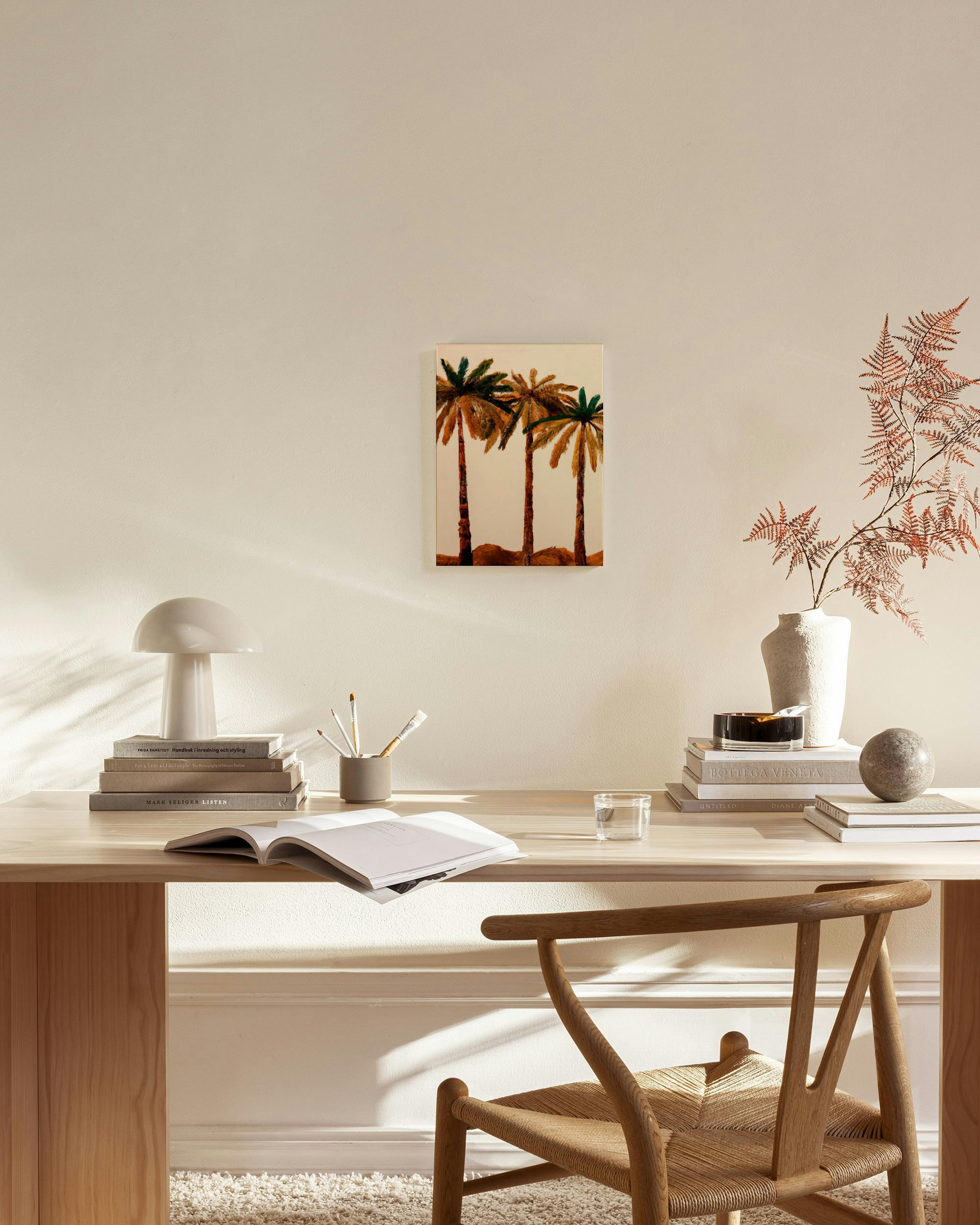 Canvas met drie palmbomen in aardetinten, hangend in een minimalistische woonkamer boven een dressoir.