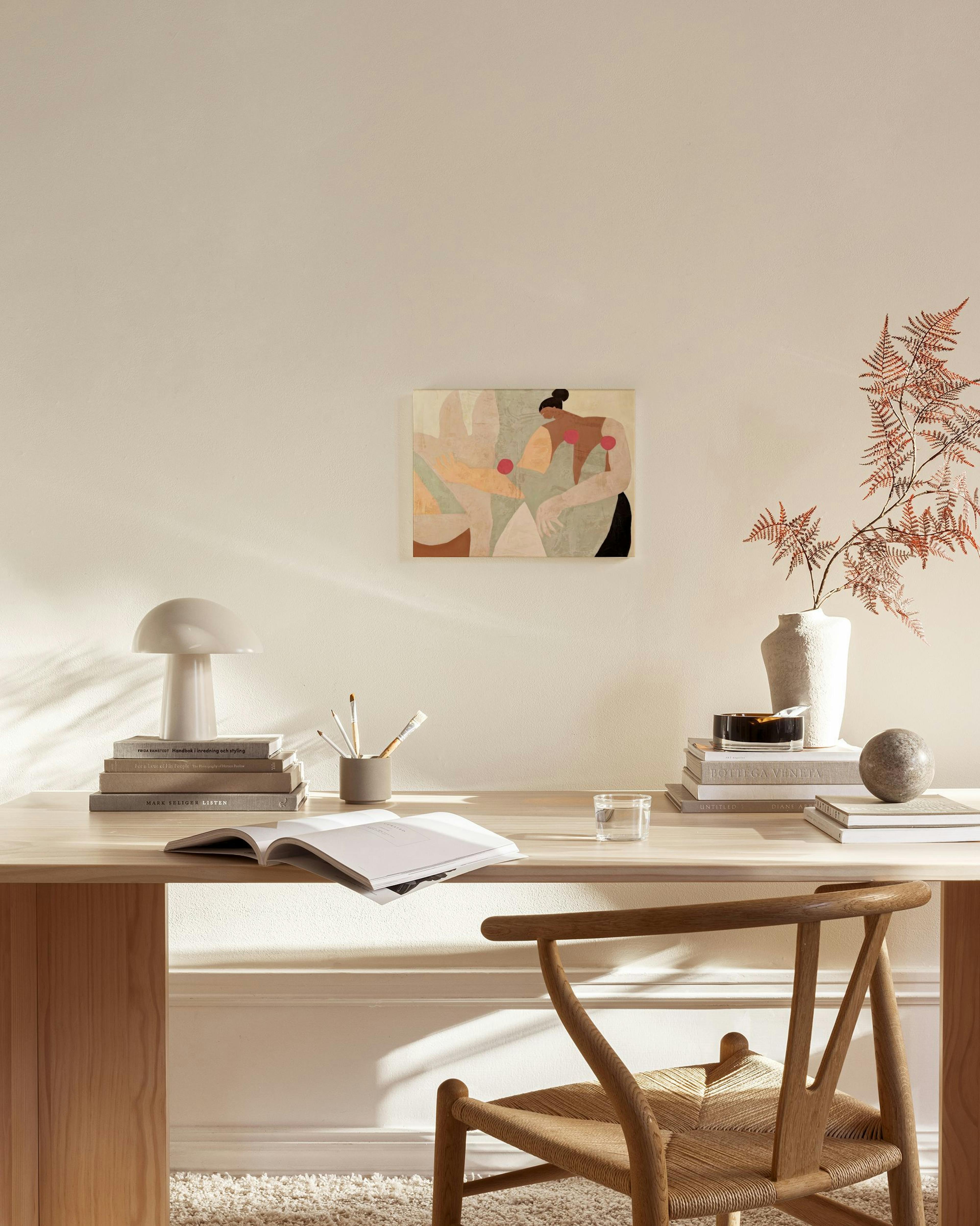 A canvas print of an abstract figure with warm tones and red circles, hanging in a minimalist living room.