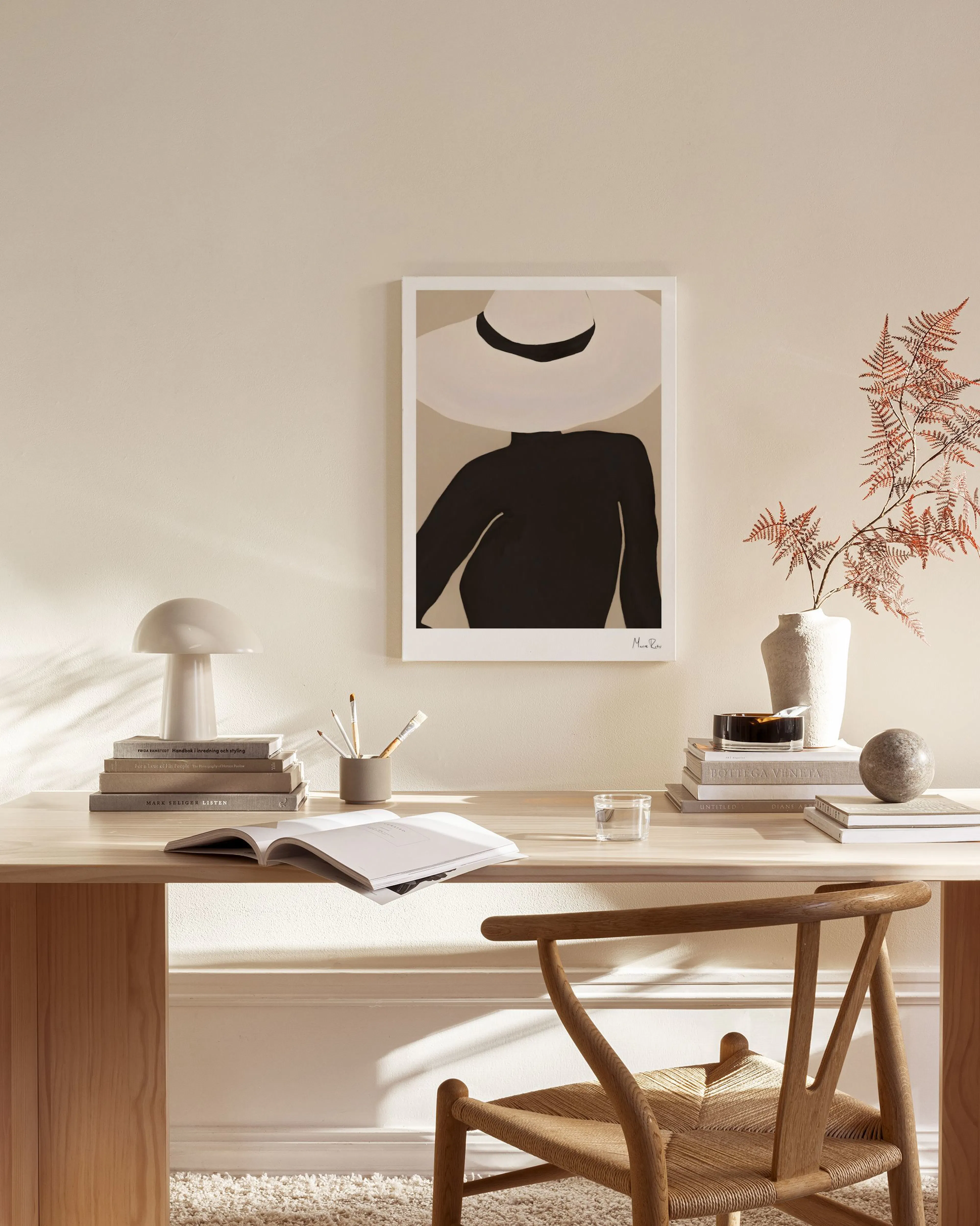 A canvas print featuring a person in a wide white hat and dark top, displayed in a bright, modern living room.