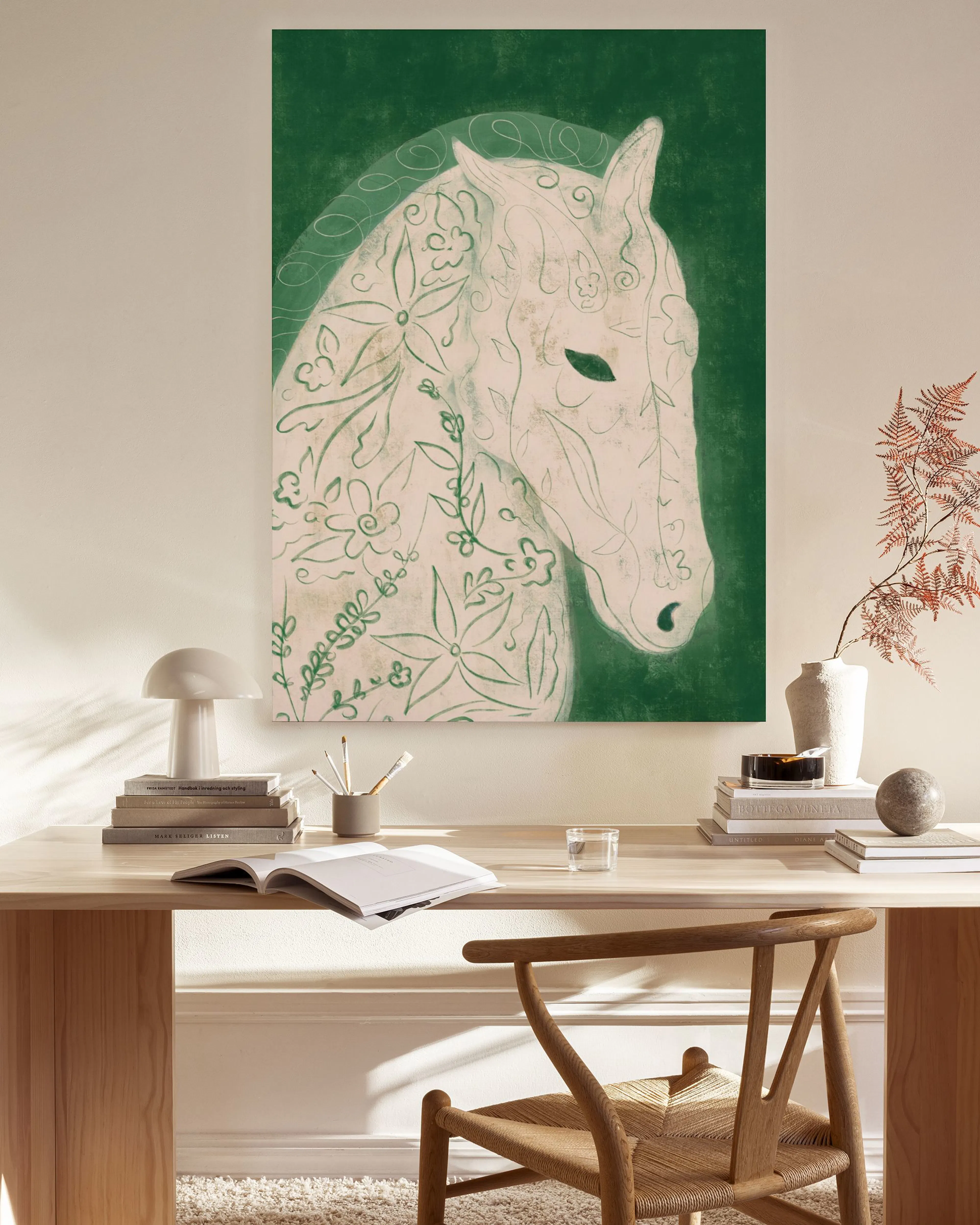 A canvas print of a white horse with green floral patterns on a dark green background, hanging in a minimalist living room.