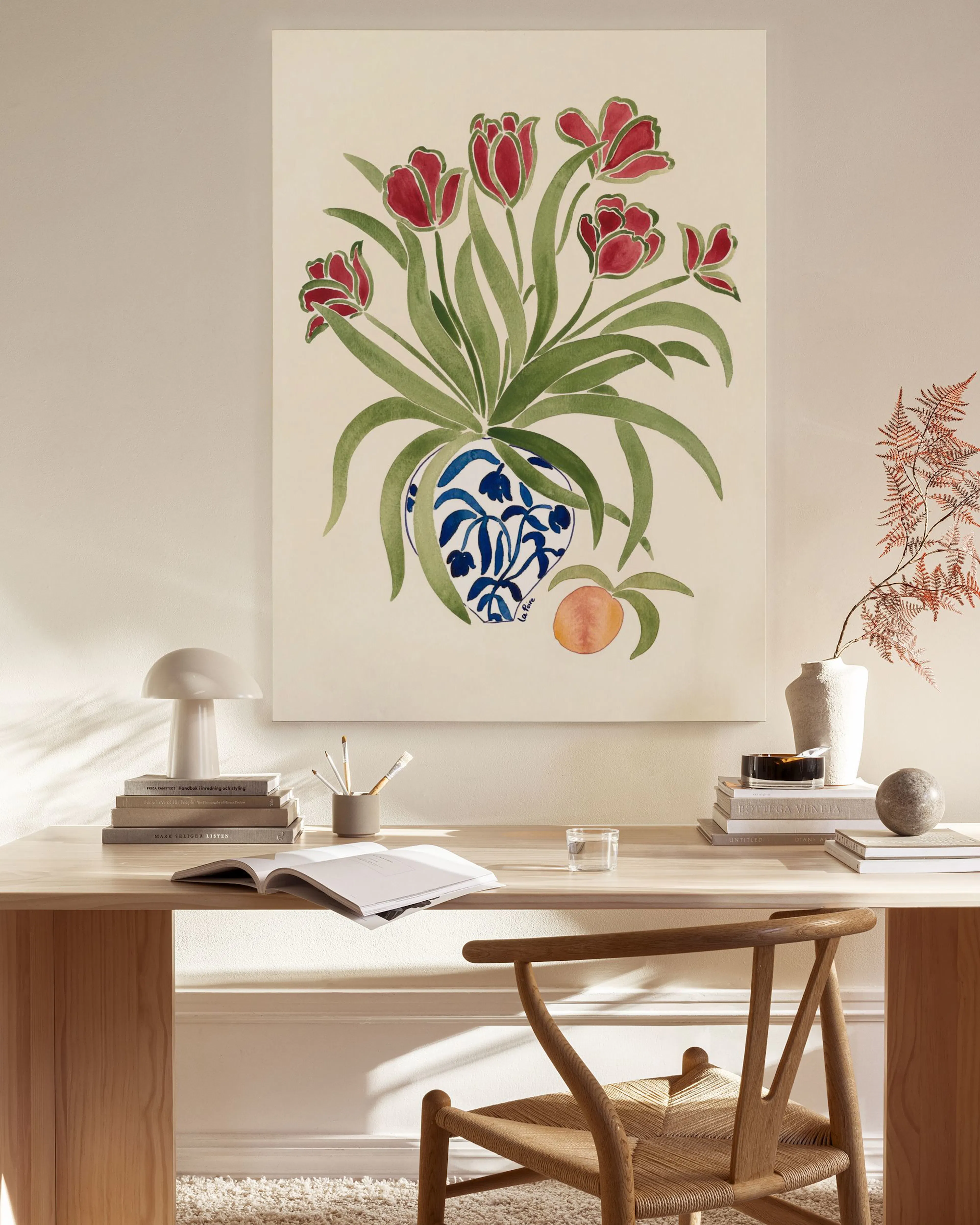 Stampa su tela con tulipani rossi in vaso blu e arancia, appesa in un soggiorno moderno e luminoso.
