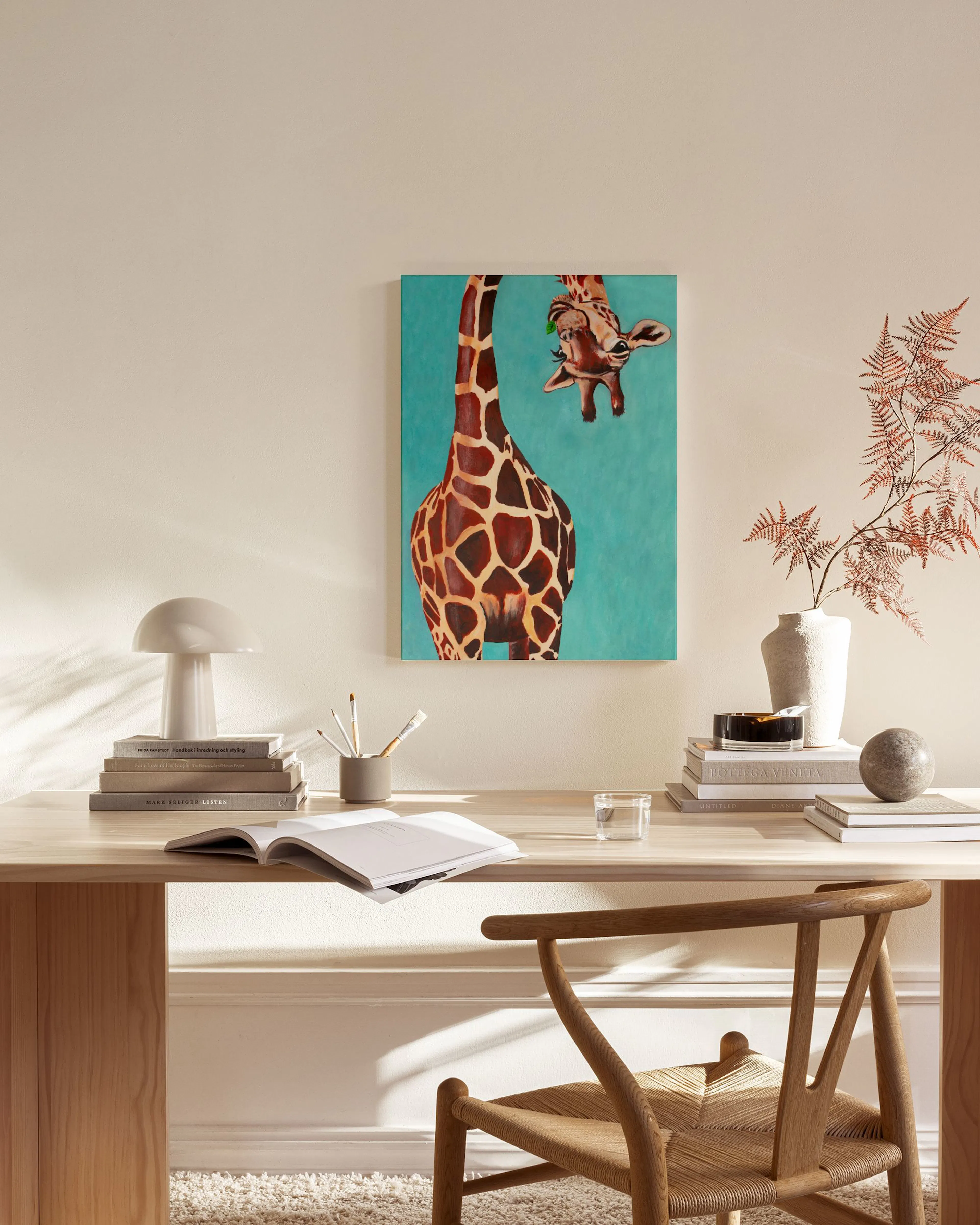 En canvastavla med en giraff som sträcker sig efter löv, hänger i ett ljust vardagsrum med trädetaljer.