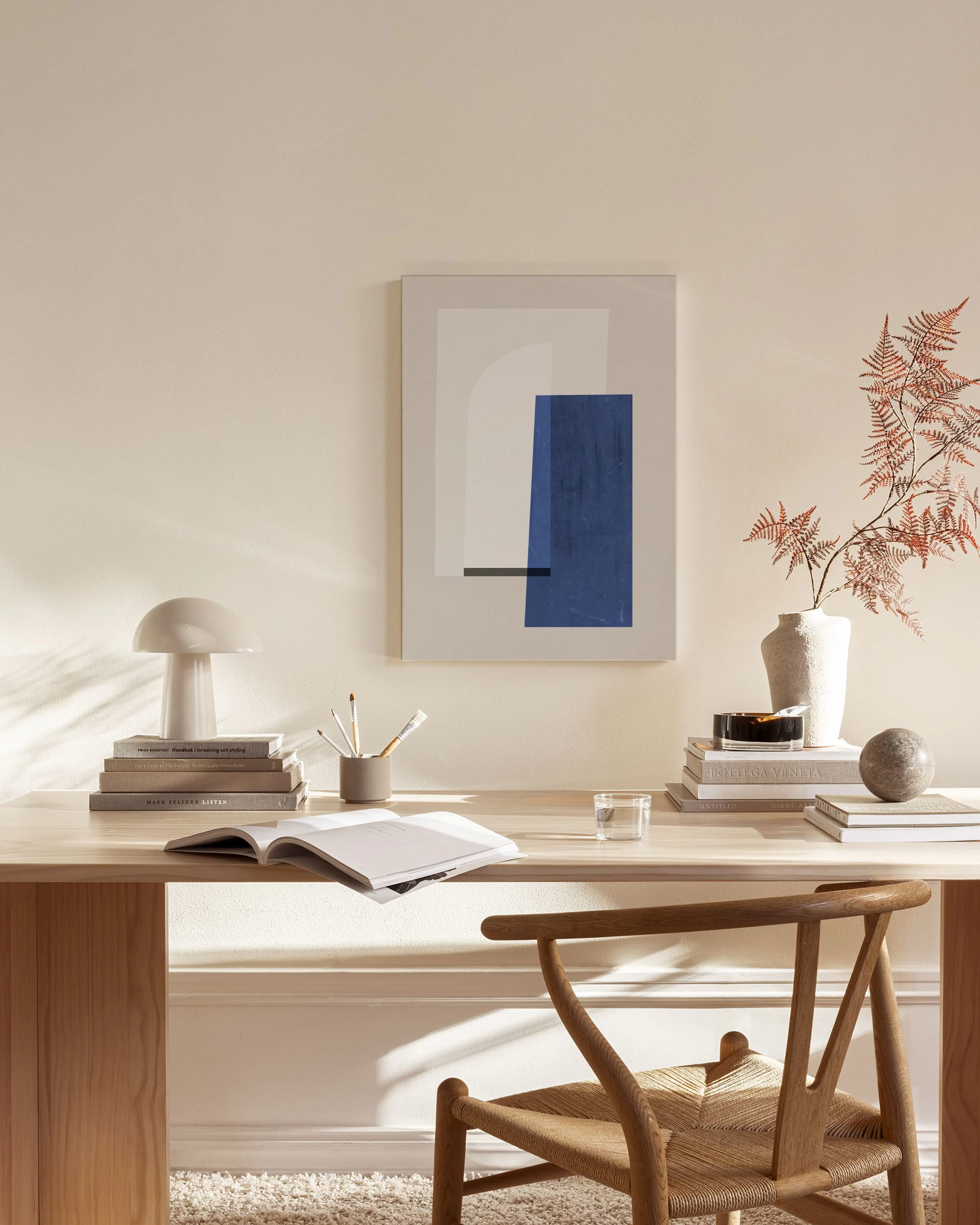 Abstract canvas print with a prominent blue rectangle and gray geometric shapes, hanging in a minimalist living room.