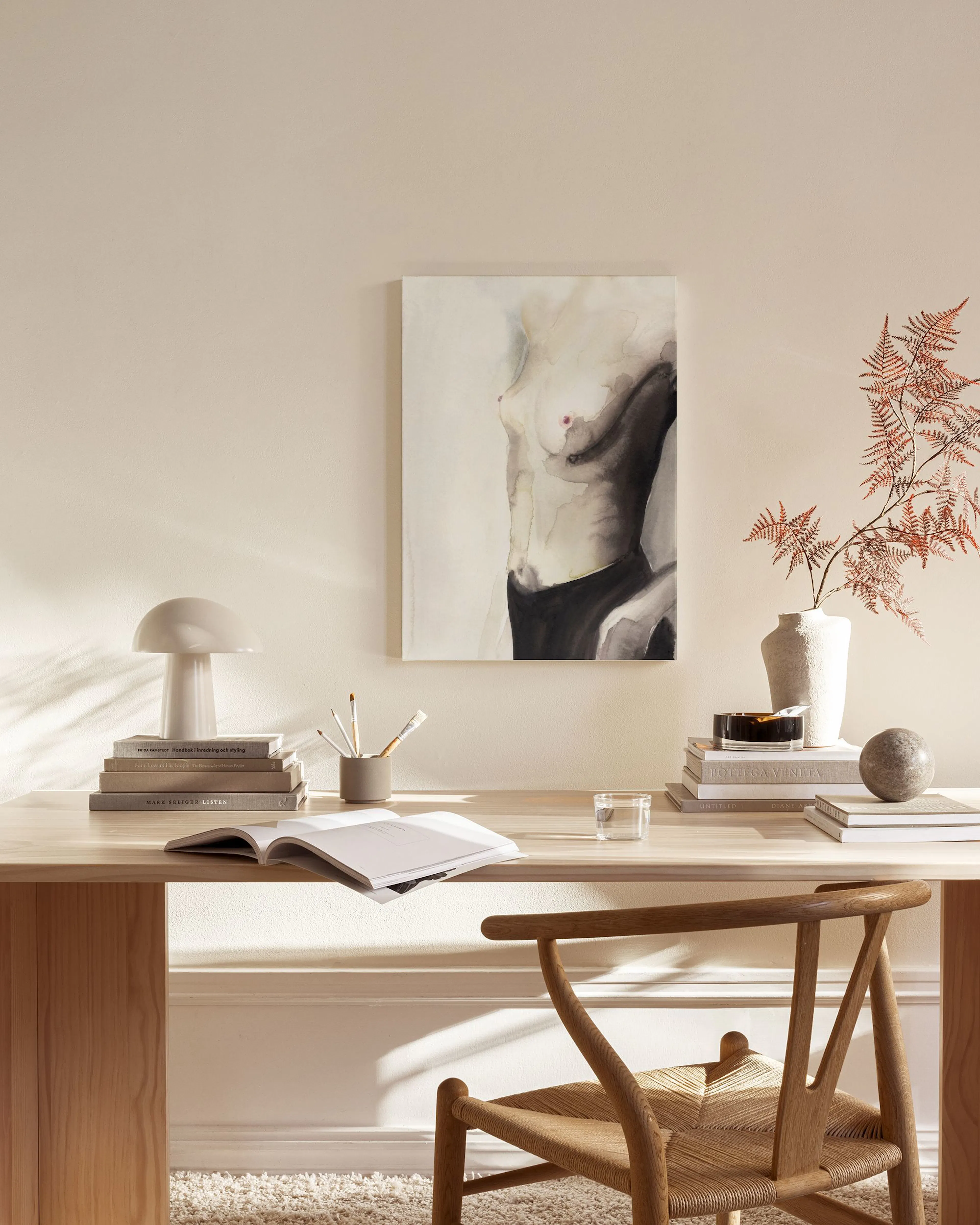 A canvas print of a female torso in black and white watercolour with a red nipple, hanging in a neutral living room.