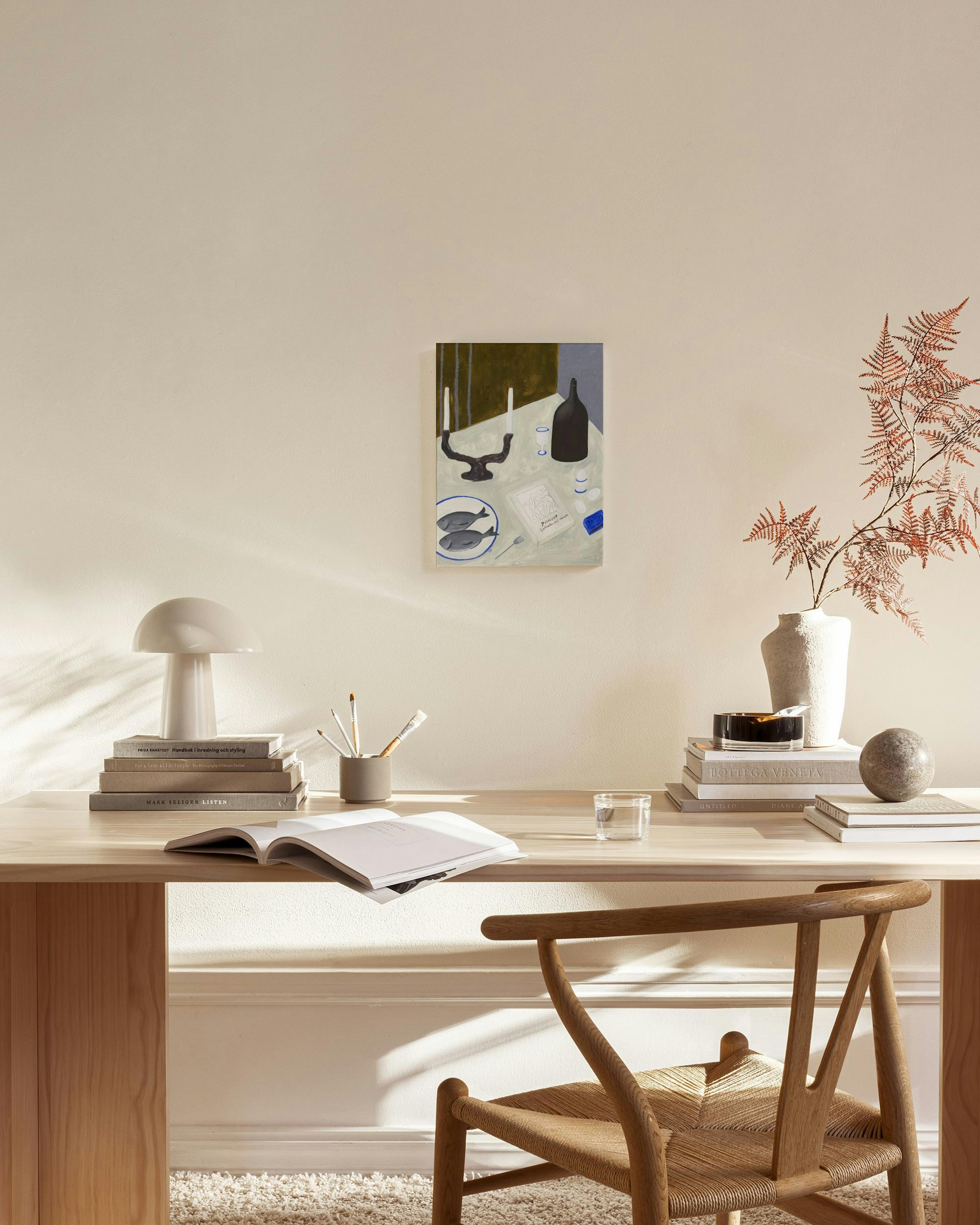 Toile représentant une nature morte avec des poissons et une bouteille, suspendue dans un salon moderne.