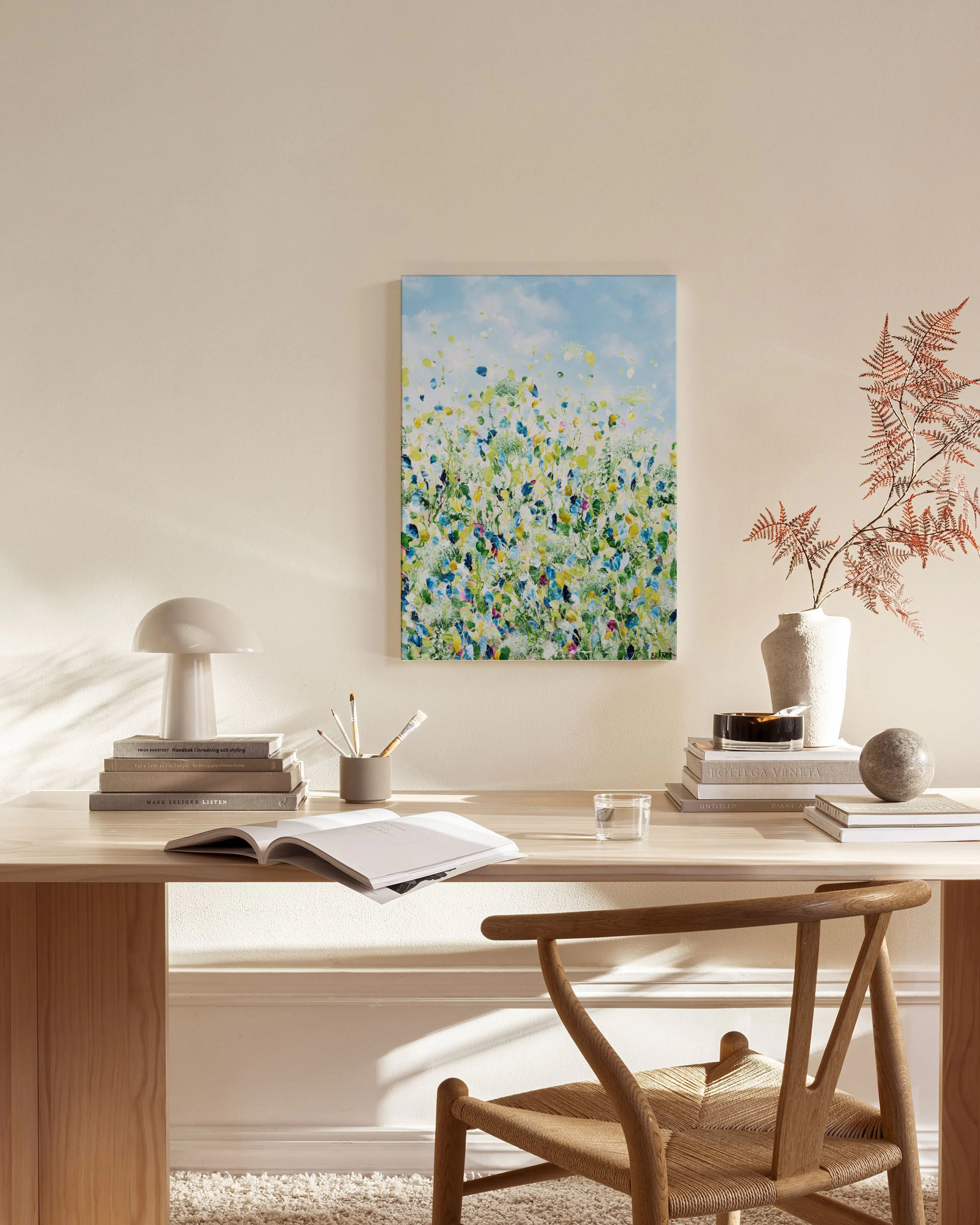 Canvas met een abstracte weergave van een bloemenveld met blauw, geel en groene accenten, hangend in een lichte woonkamer.