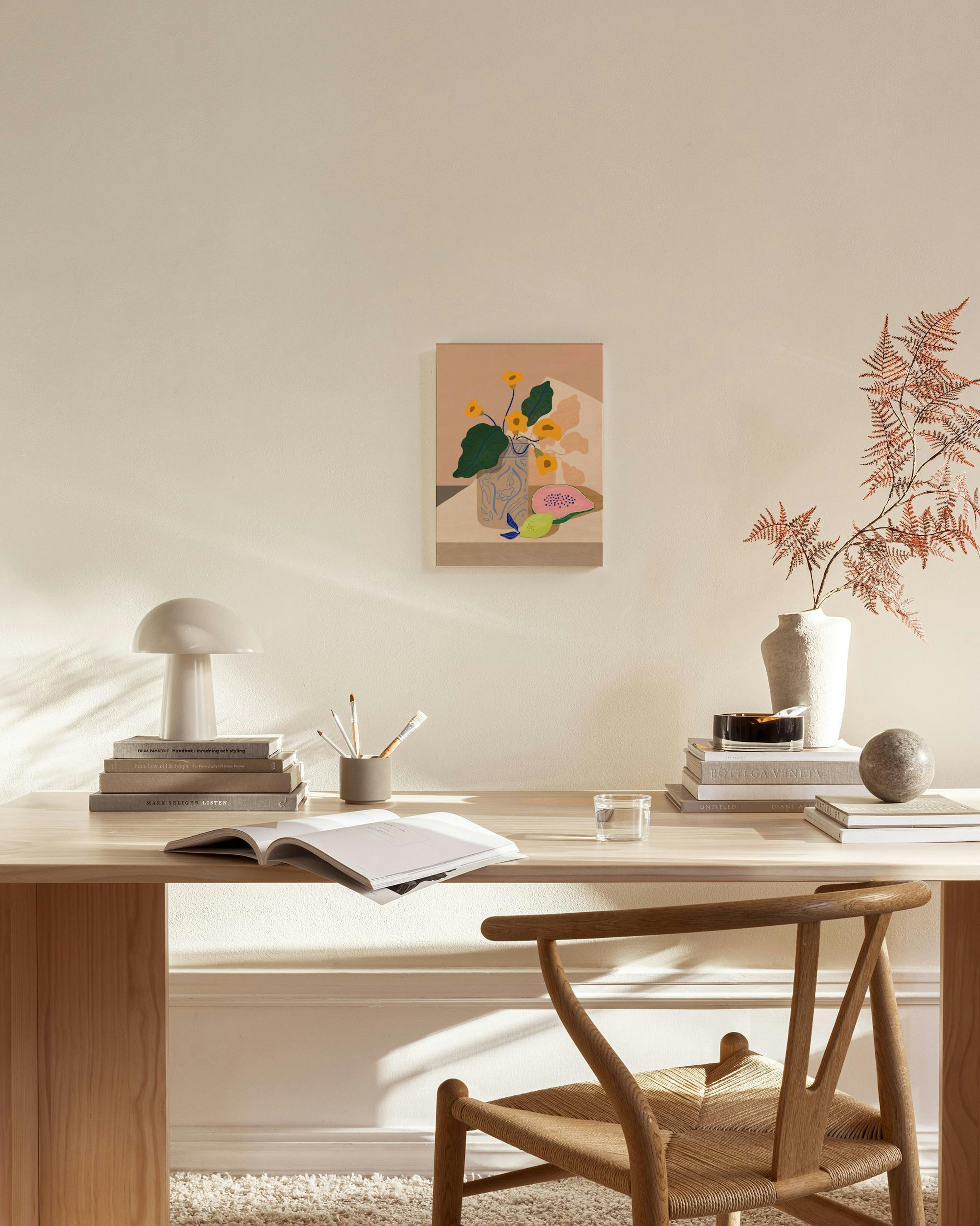 Toile aux couleurs vives représentant un vase de fleurs jaunes et des fruits, accrochée dans un salon lumineux.