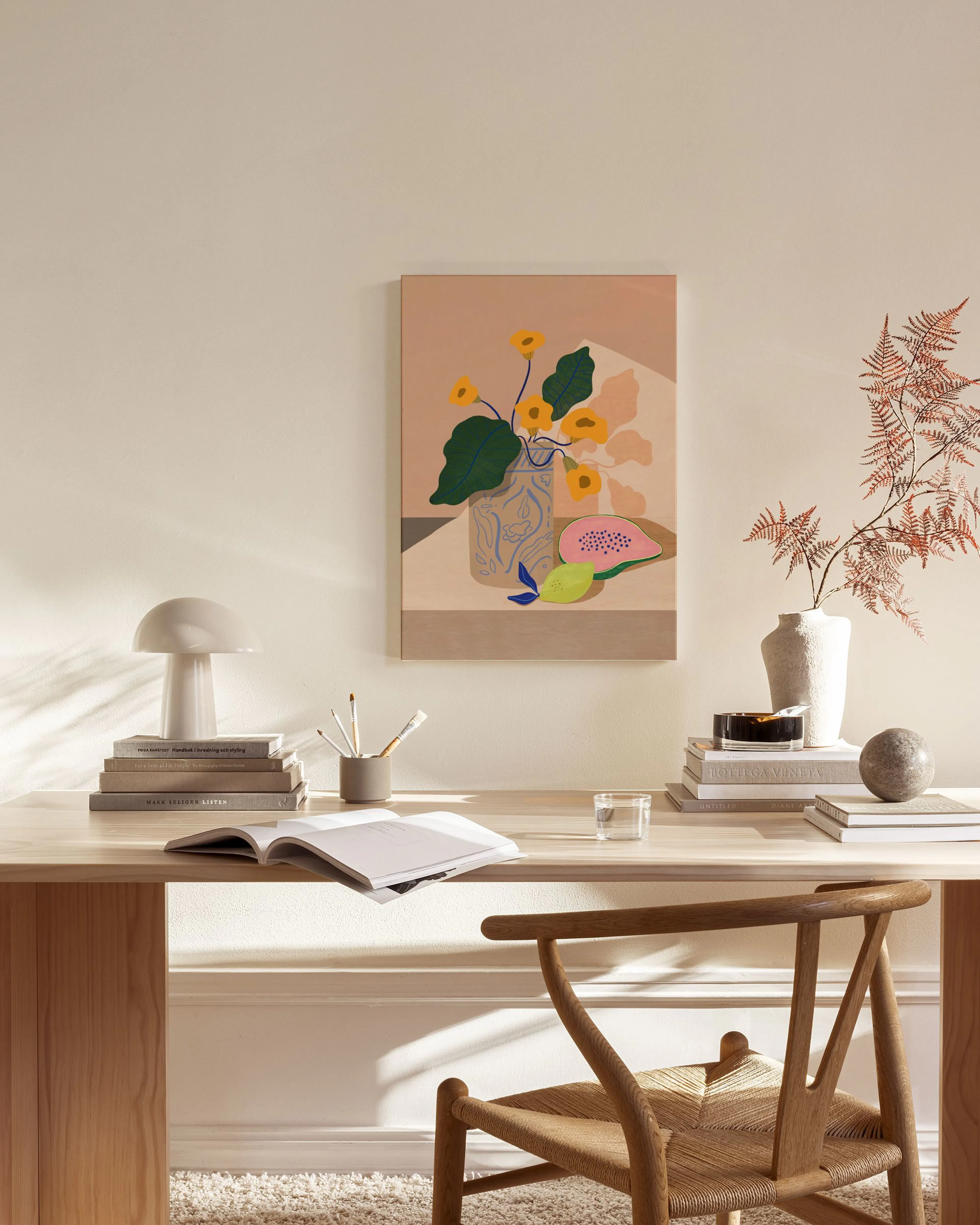 Leinwandbild mit gelben Blüten in einer blauen Vase und Früchten, in einem hellen Wohnzimmer über einem Sideboard.