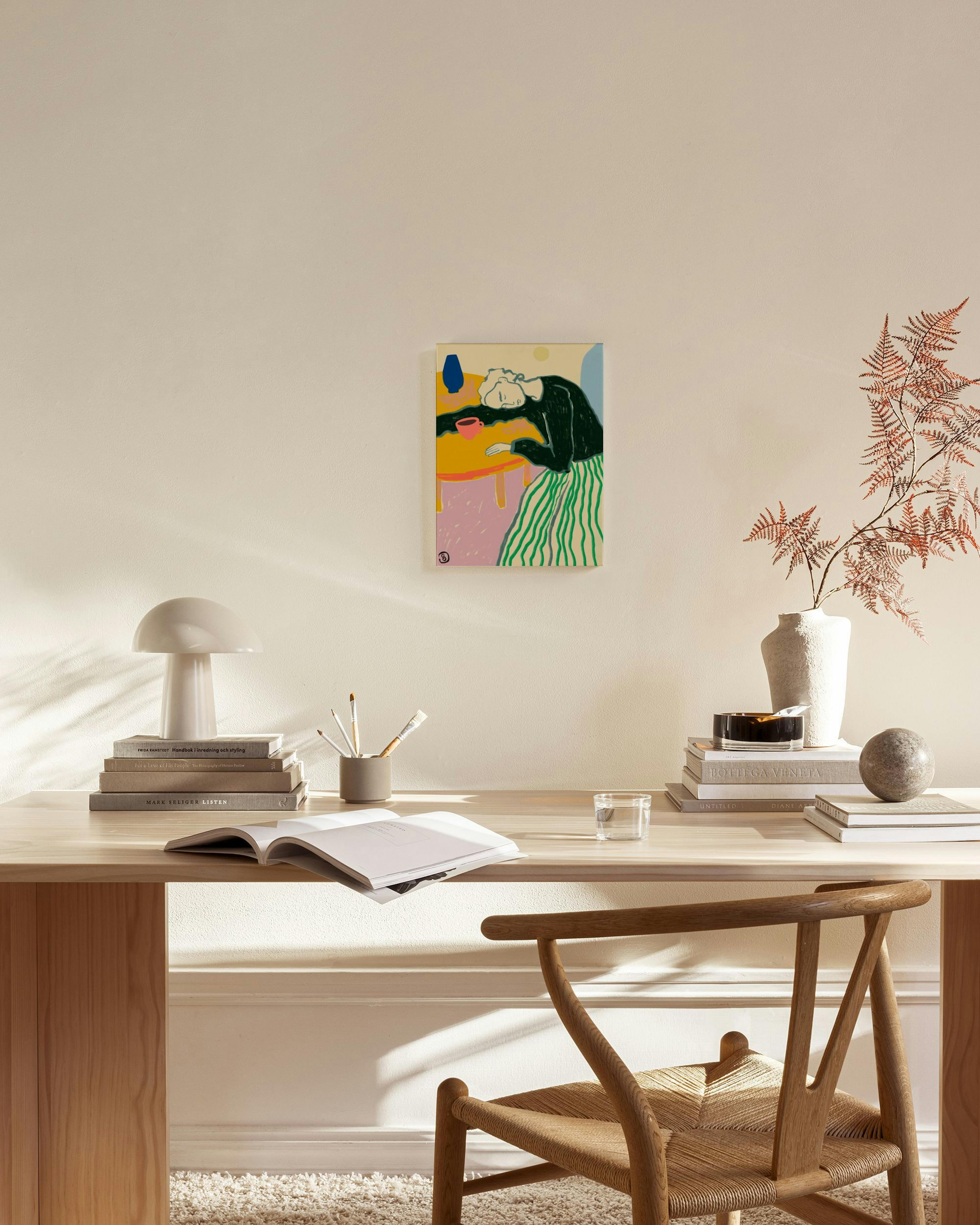 Farverigt lærred af en kvinde med hovedet på et bord, hængende i en stue over et træmøbel.