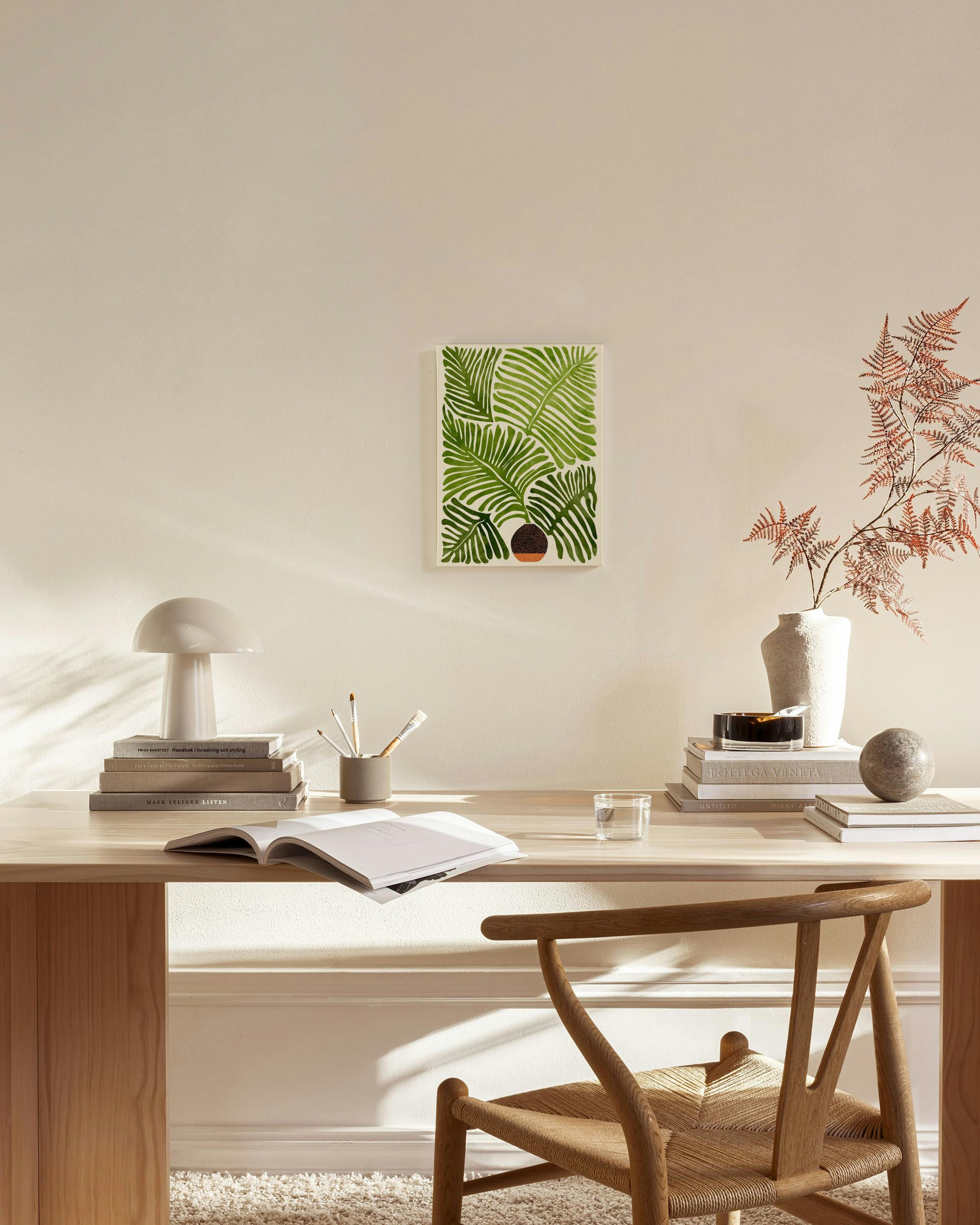 Canvas print of green palm leaves in an abstract brown pot, hanging in a bright, minimalist living room.