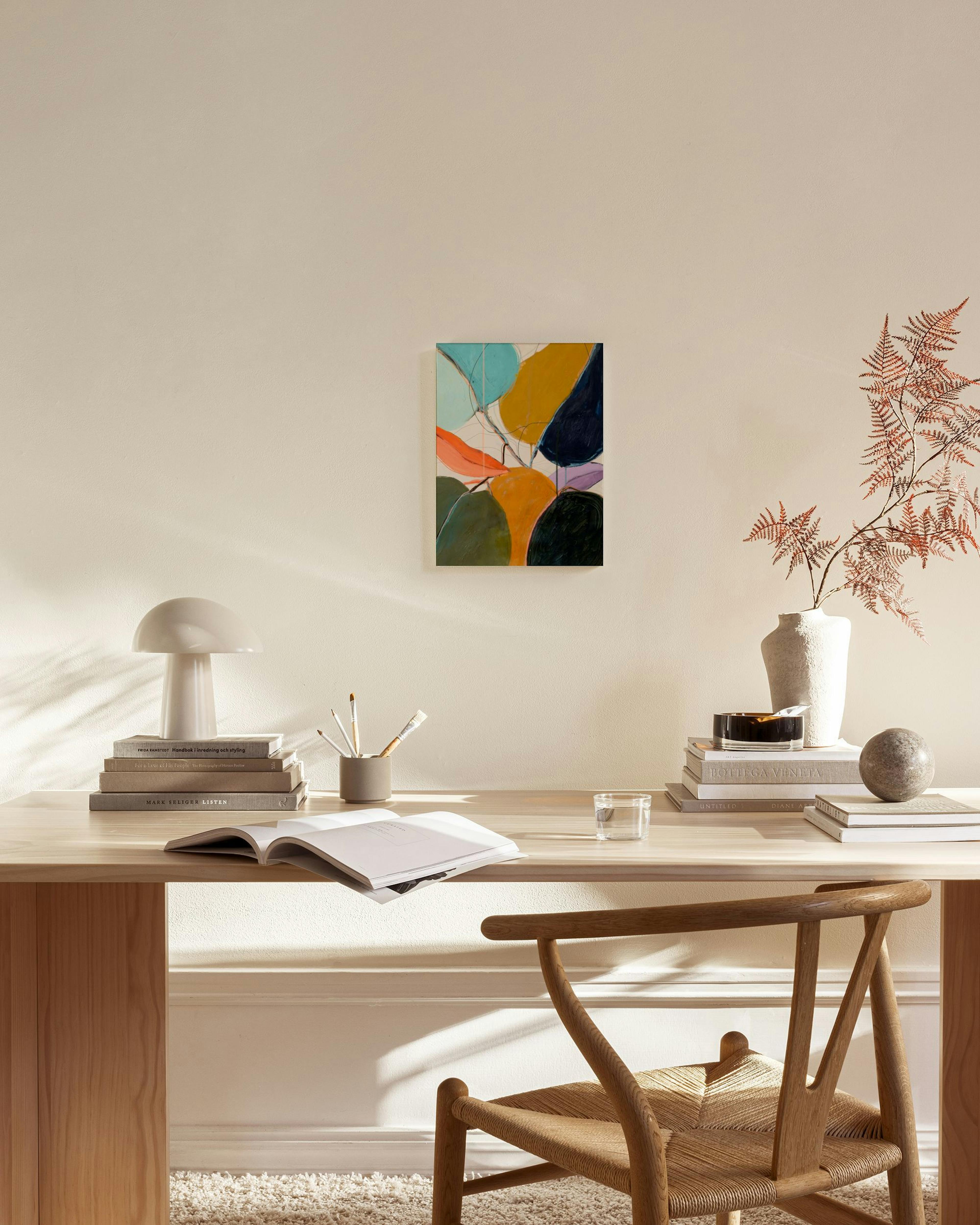 Obraz na plátne s abstraktnými organickými tvarmi v odtieňoch modrej, horčicovej, oranžovej a zelenej visí v modernej obývačke.
