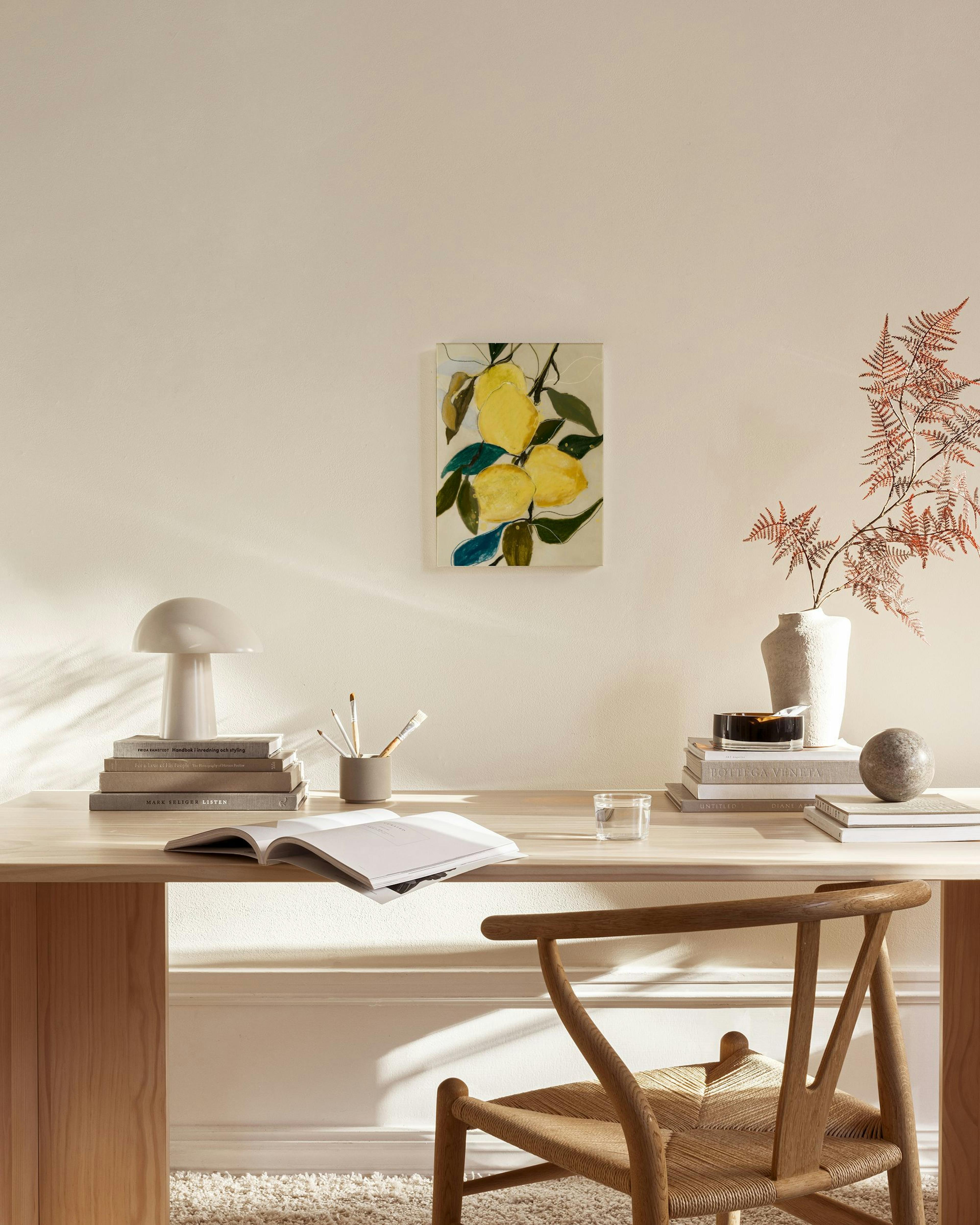 Leinwandbild mit gelben Zitronen und grünen Blättern. Hängt in einem hellen Wohnzimmer über einem Sideboard.