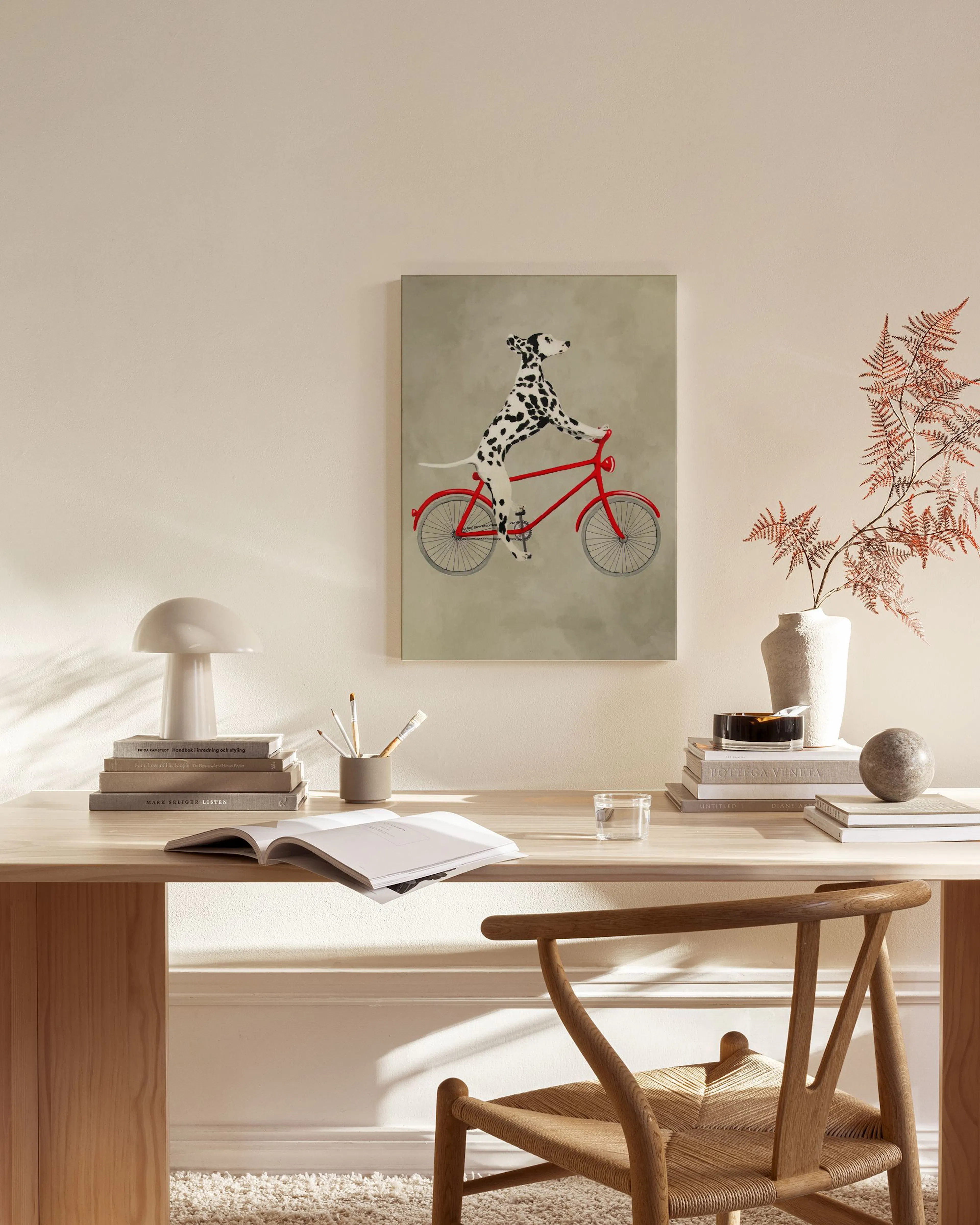 Canvas met een Dalmatiër op een rode fiets, hangend boven een houten dressoir in een lichte woonkamer.