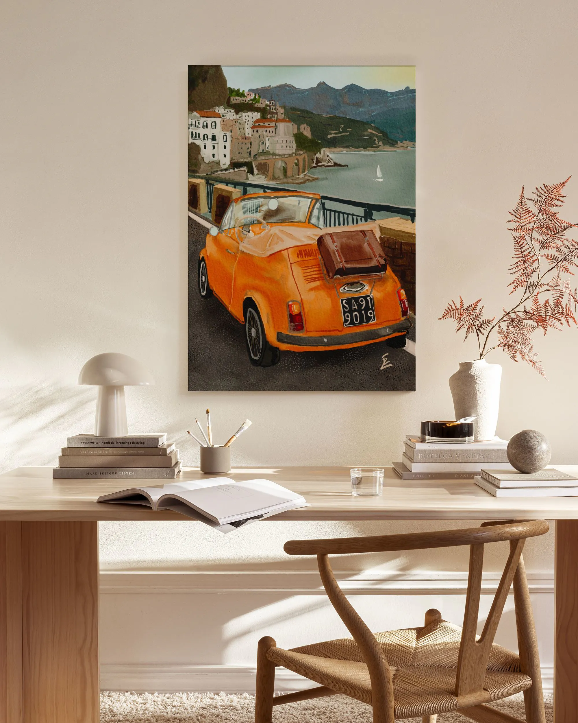 Tela com um carro Fiat 500 laranja com bagagem no porta-bagagens, numa estrada costeira italiana, pendurada numa sala de estar m