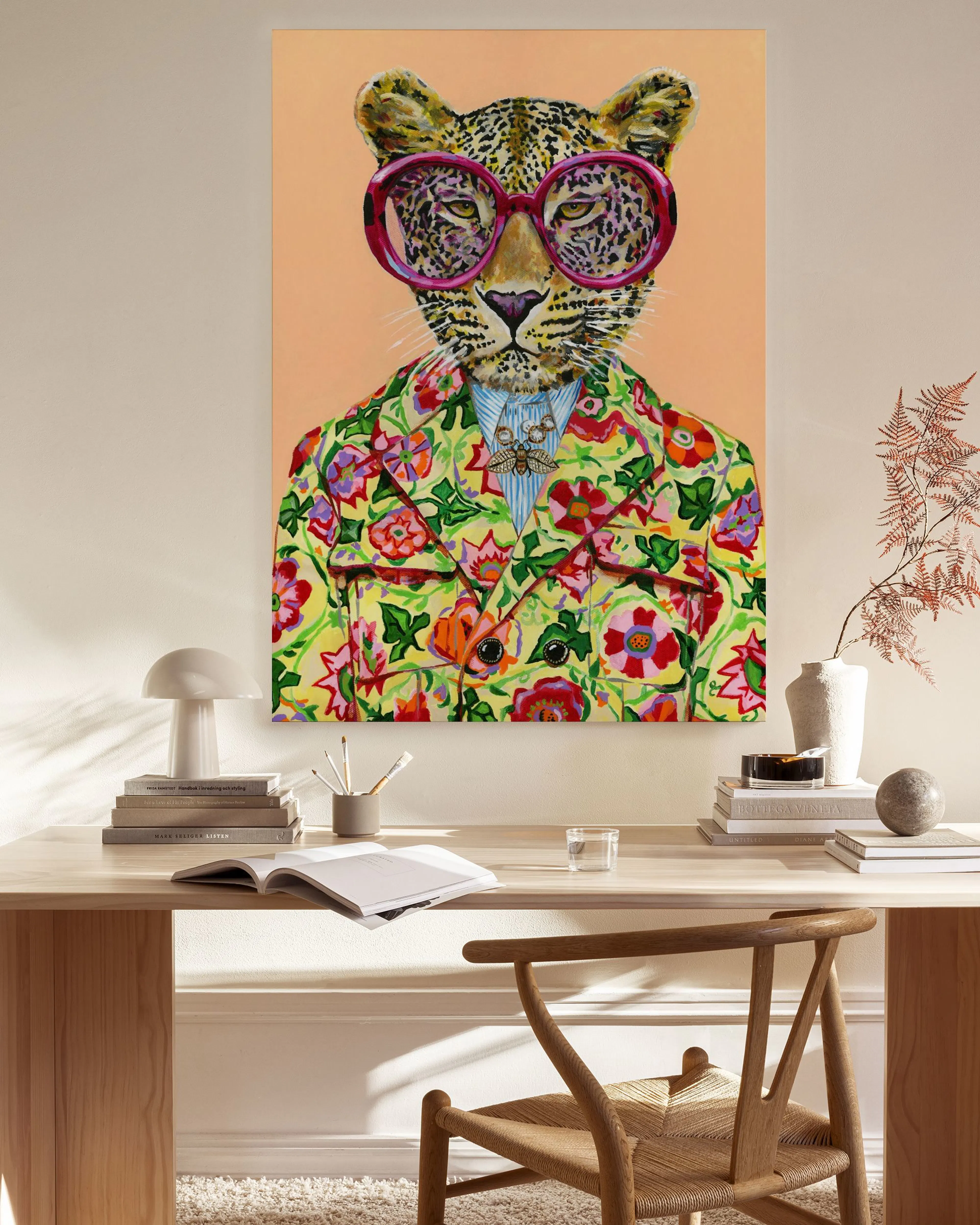 Canvas van een luipaard met roze zonnebril en bloemenjas, hangend in een moderne woonkamer boven een houten dressoir.
