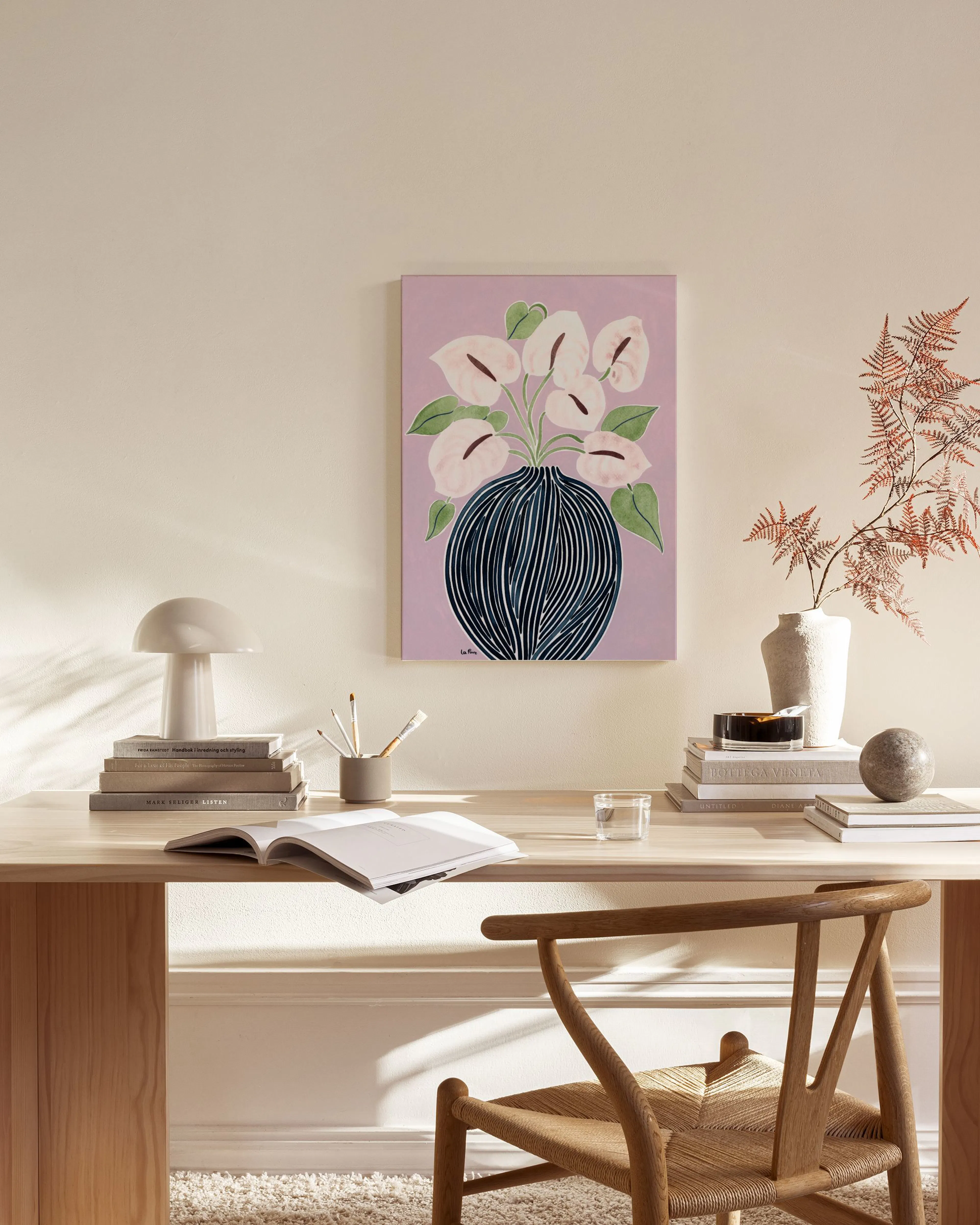 A canvas print of white anthurium flowers in a dark striped vase, on a pastel purple background, hanging in a living room.