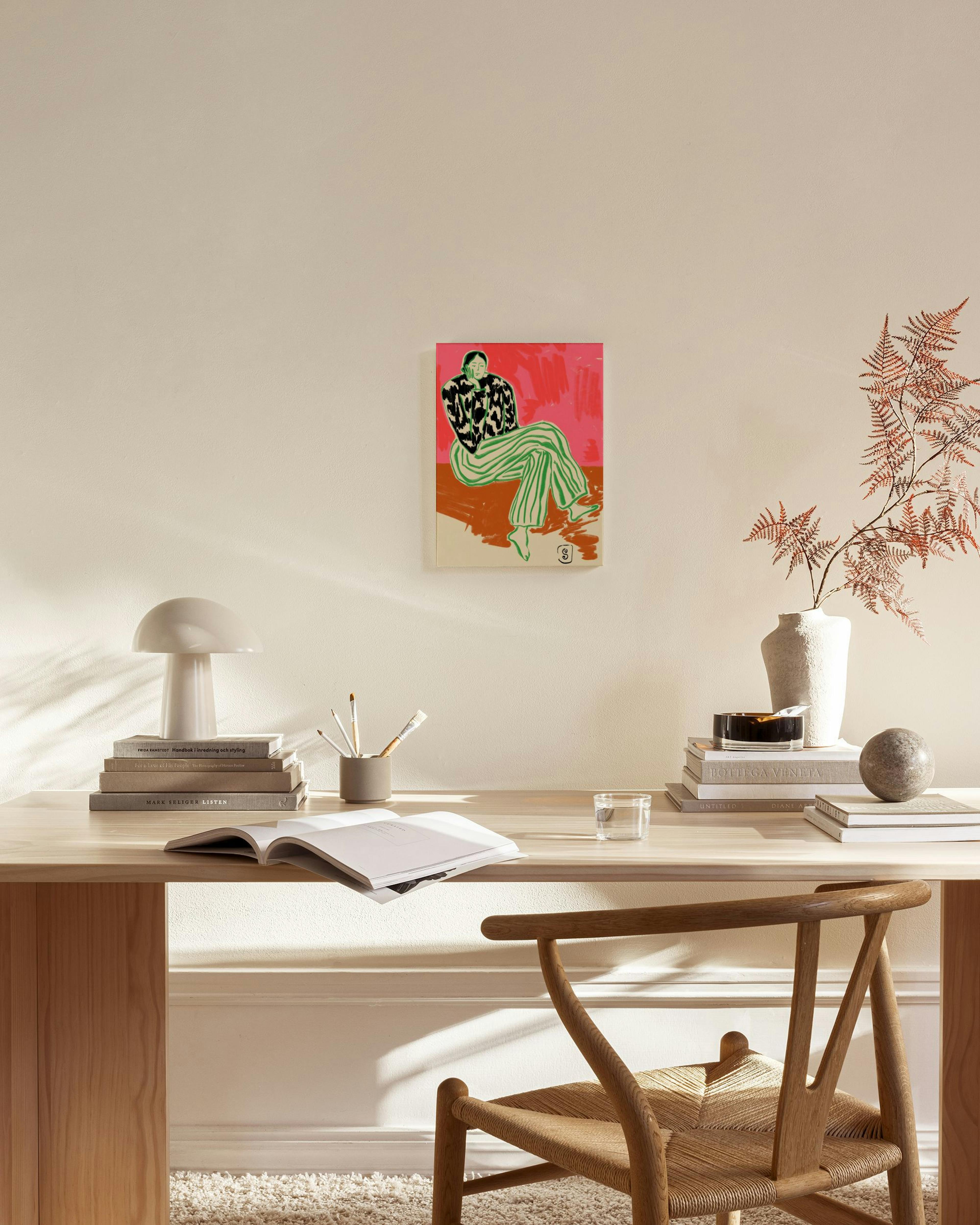 A canvas print of a person in green striped pants and a black and white top on a red and orange background, hanging in a modern 