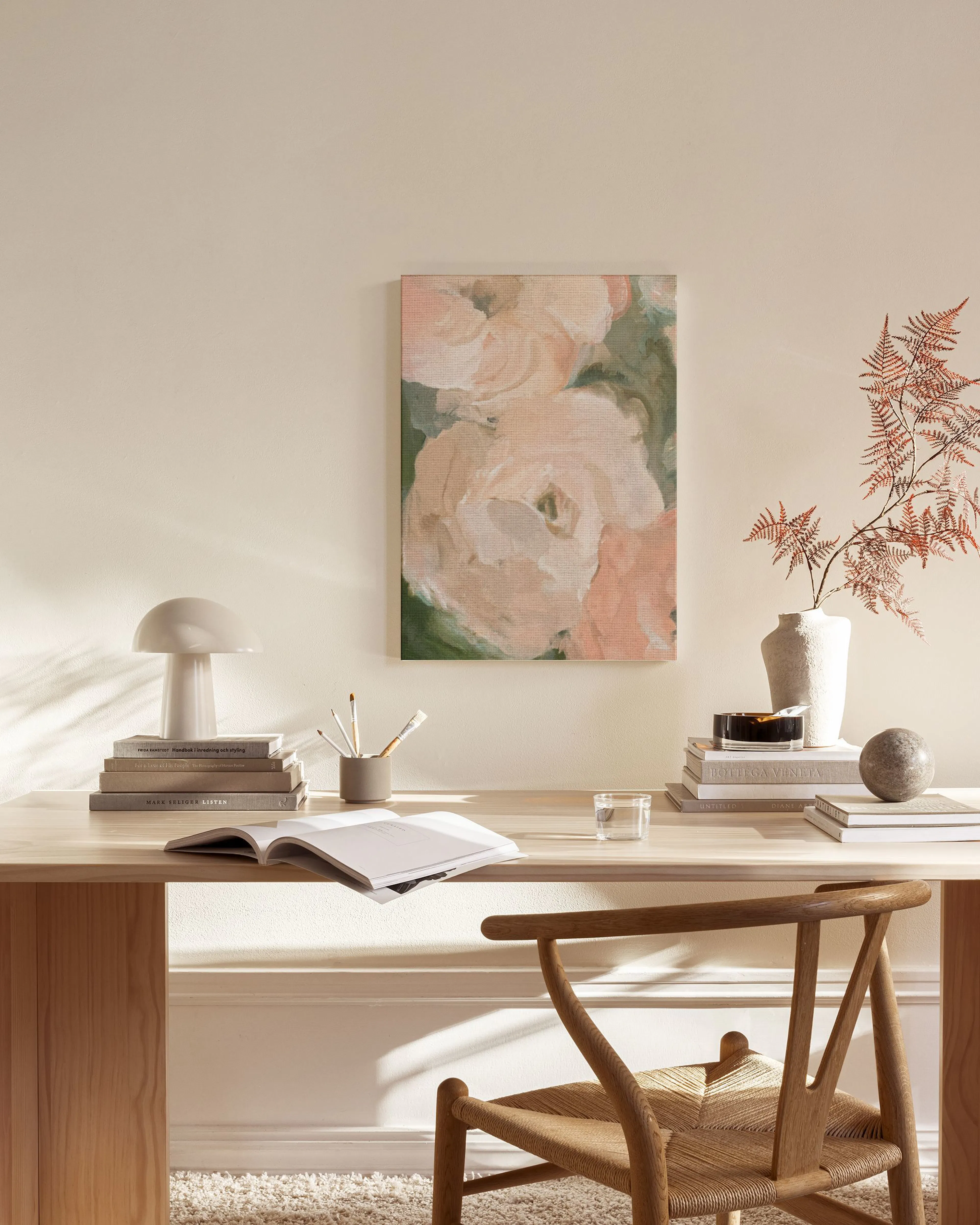 Canvas met roze bloemen en groene bladeren, hangend in een neutrale woonkamer boven een houten dressoir.