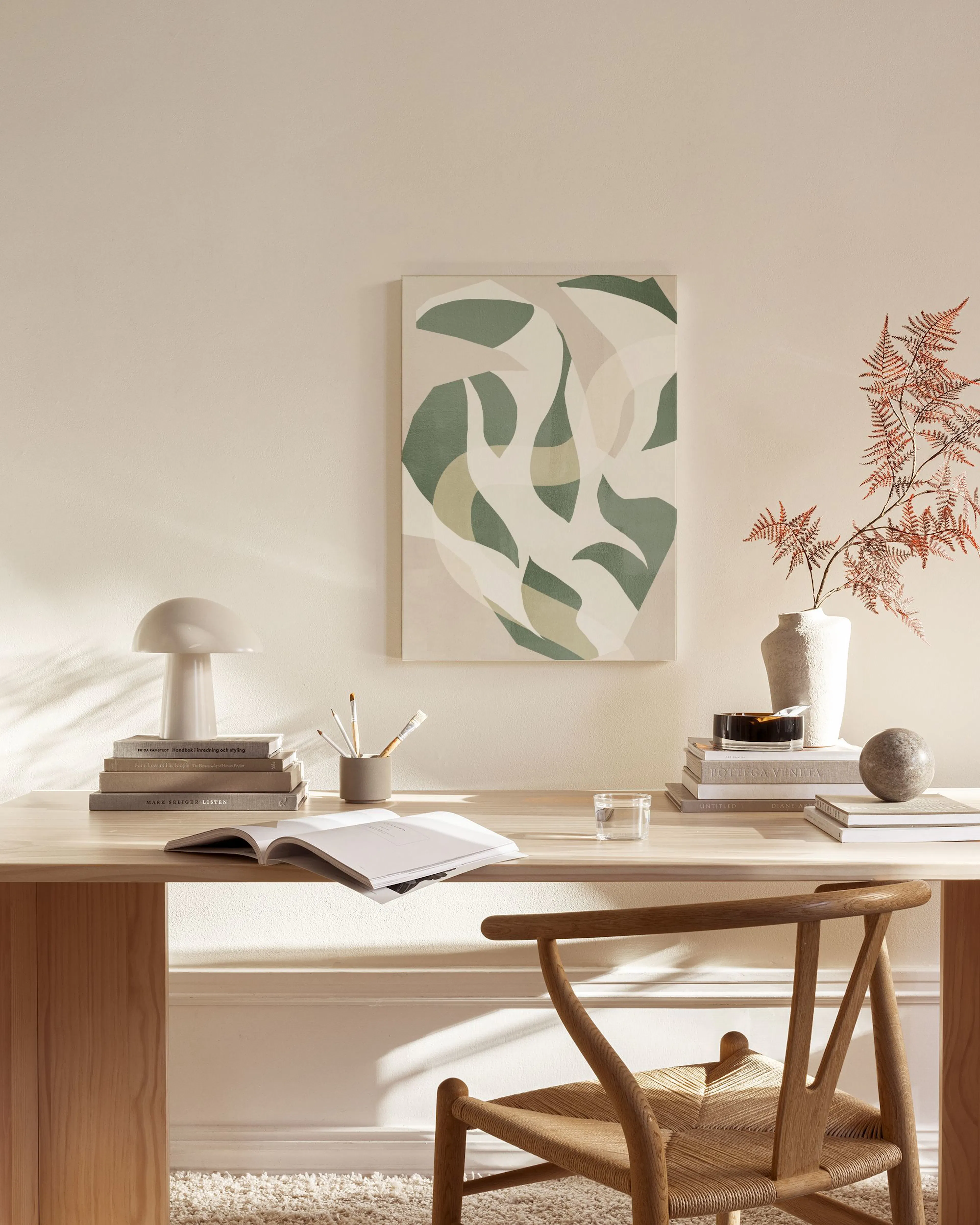 Leinwandbild mit organischen Formen in Grün- und Beigetönen, hängt über einer Holzkommode im Wohnzimmer.