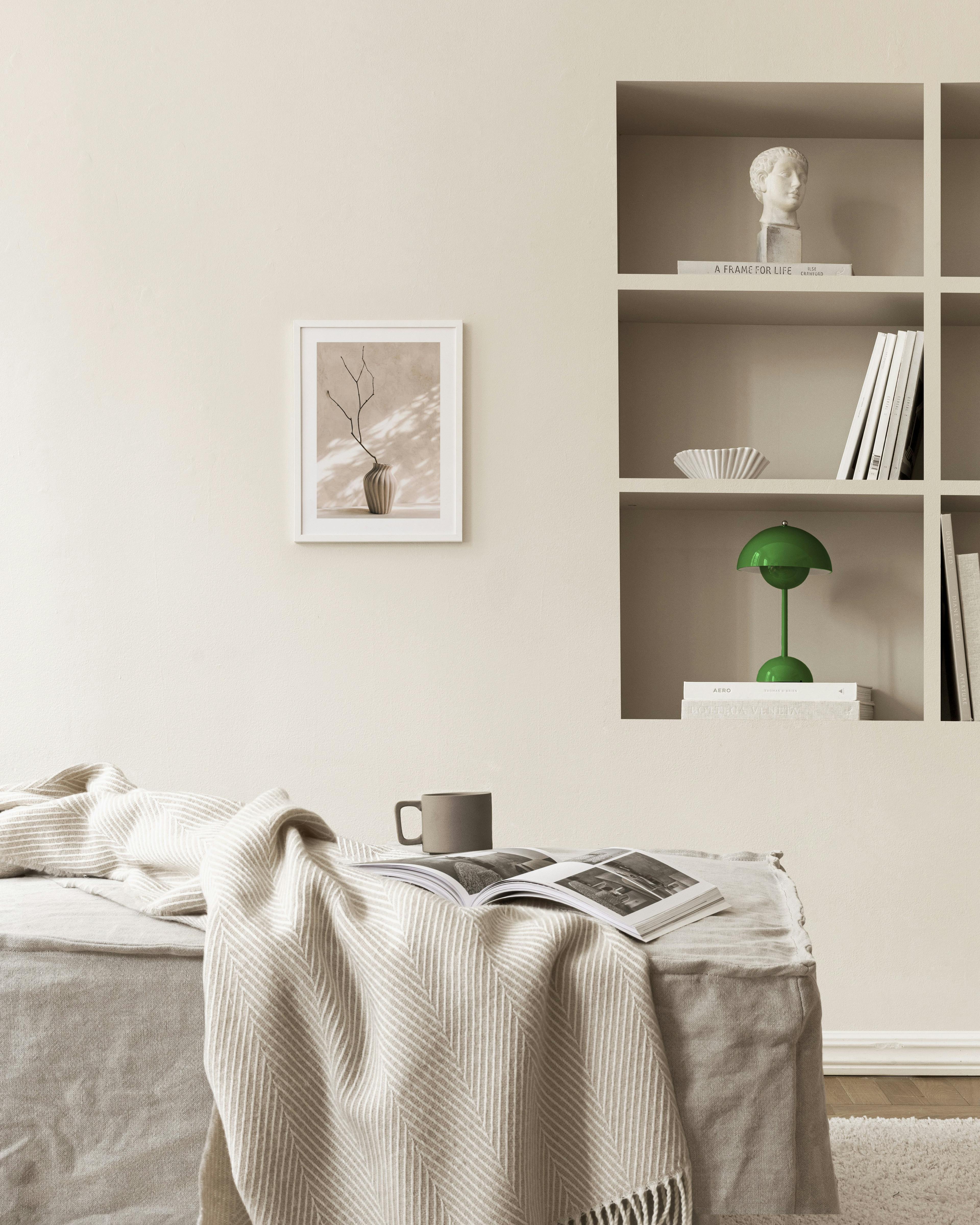 Poster mit einer beigen Vase und einem Ast, an einer beigefarbenen Wand in einem modernen Raum.