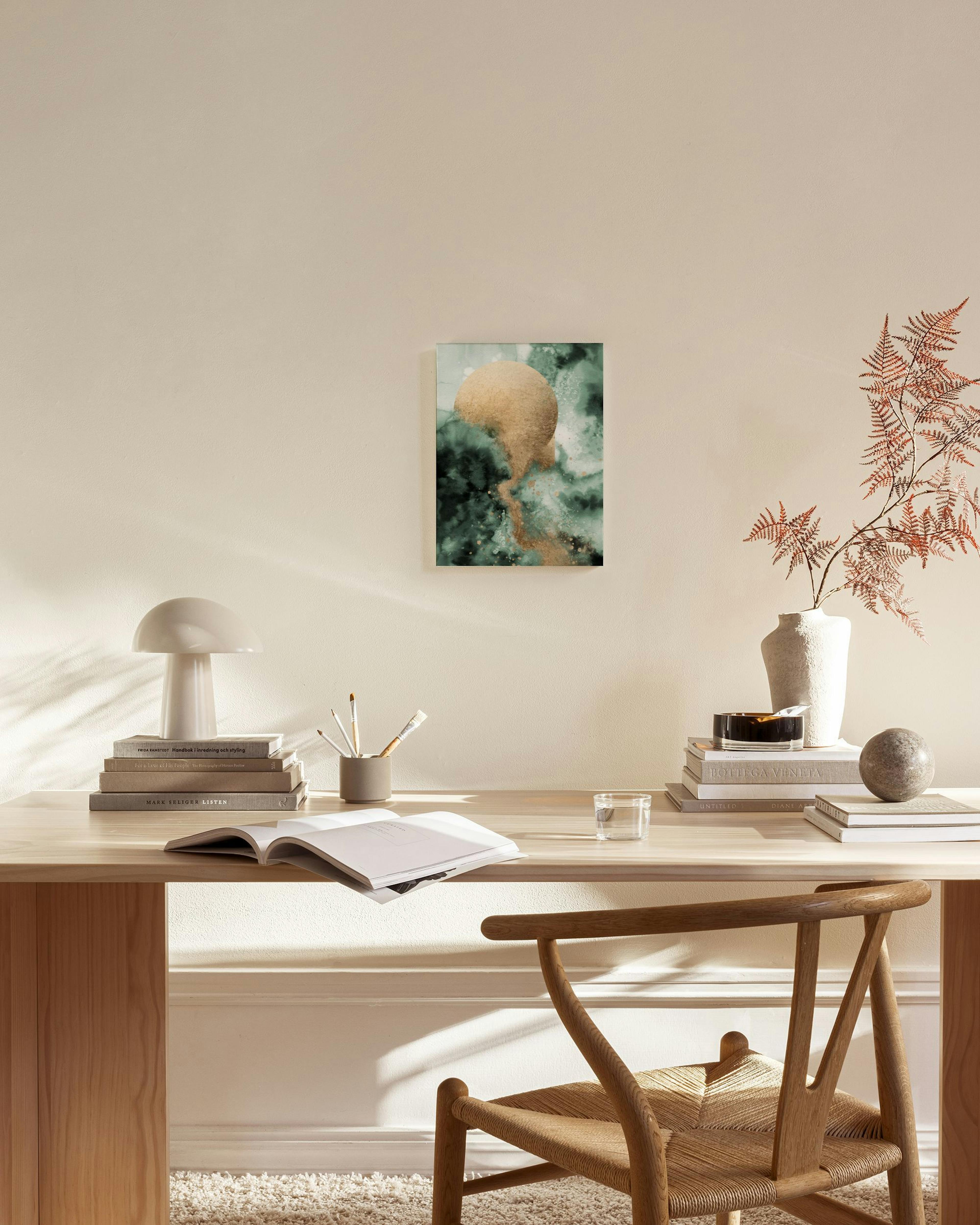 Lerretsbilde med gullfarget eggform mot grønn og hvit bakgrunn, henger i en lys stue.