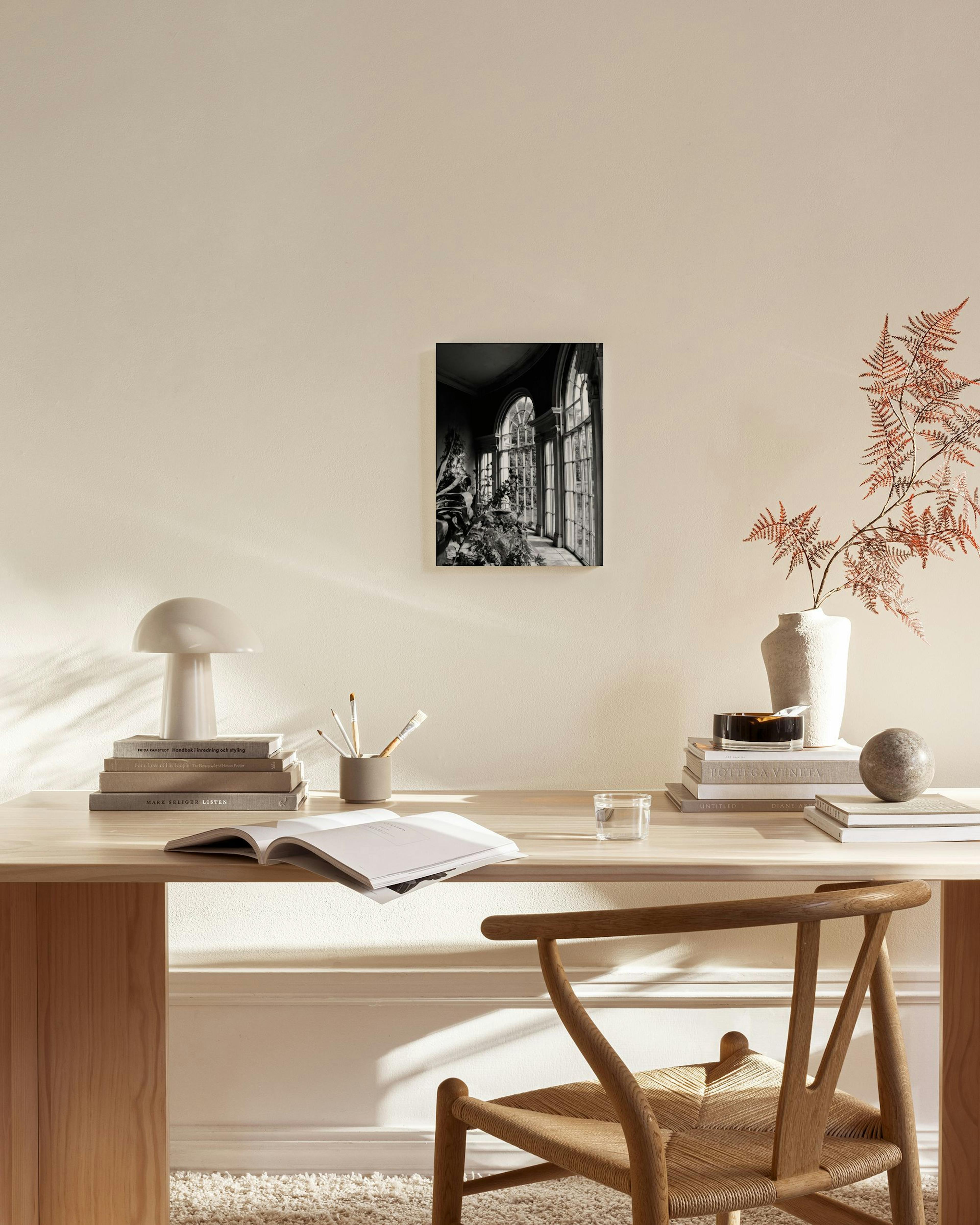 Black and white photography print of a grand interior with large arched windows, hanging in a minimalist living room.