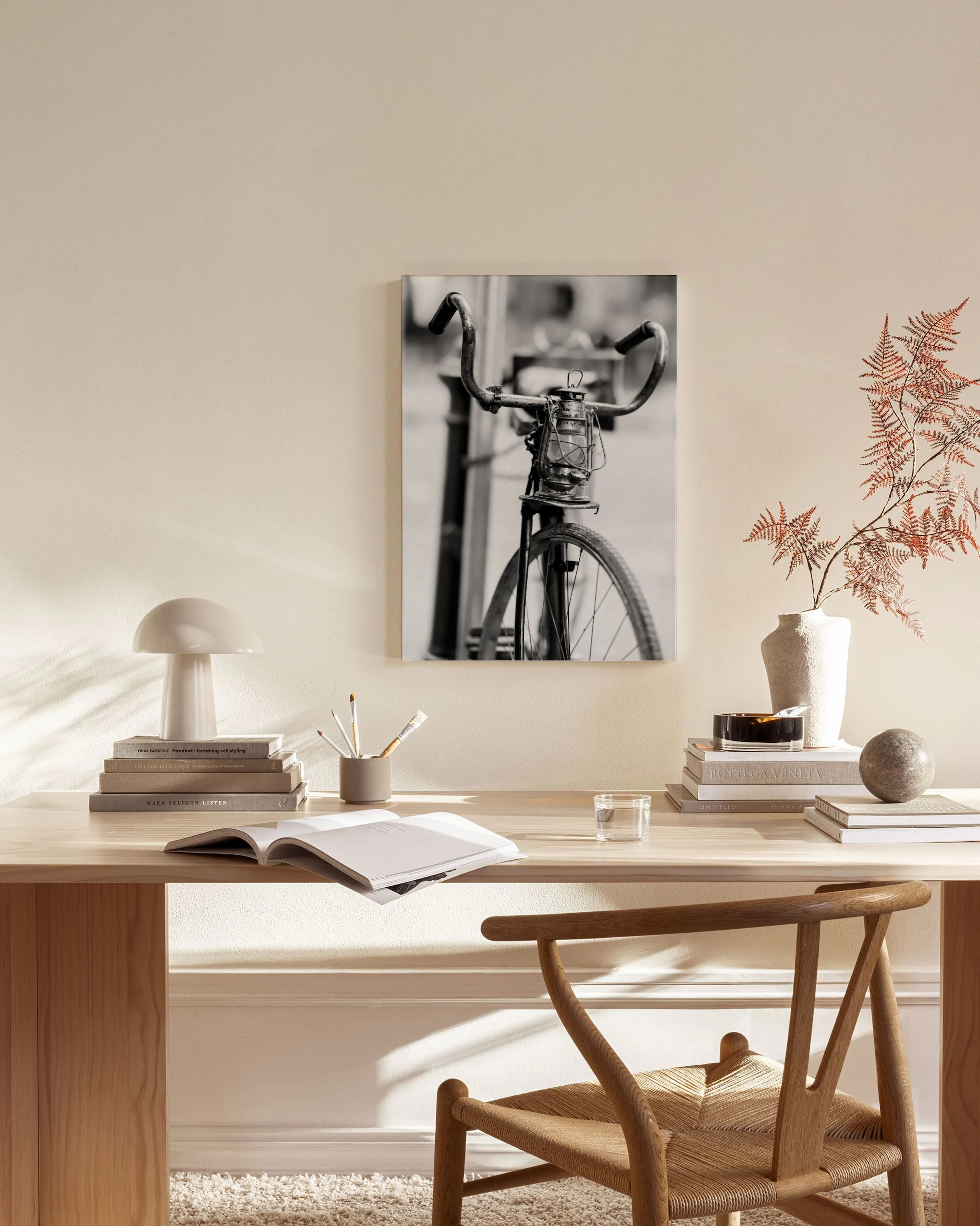 Lienzo monocromático de una bicicleta clásica con un farol, expuesto en una sala de estar moderna.