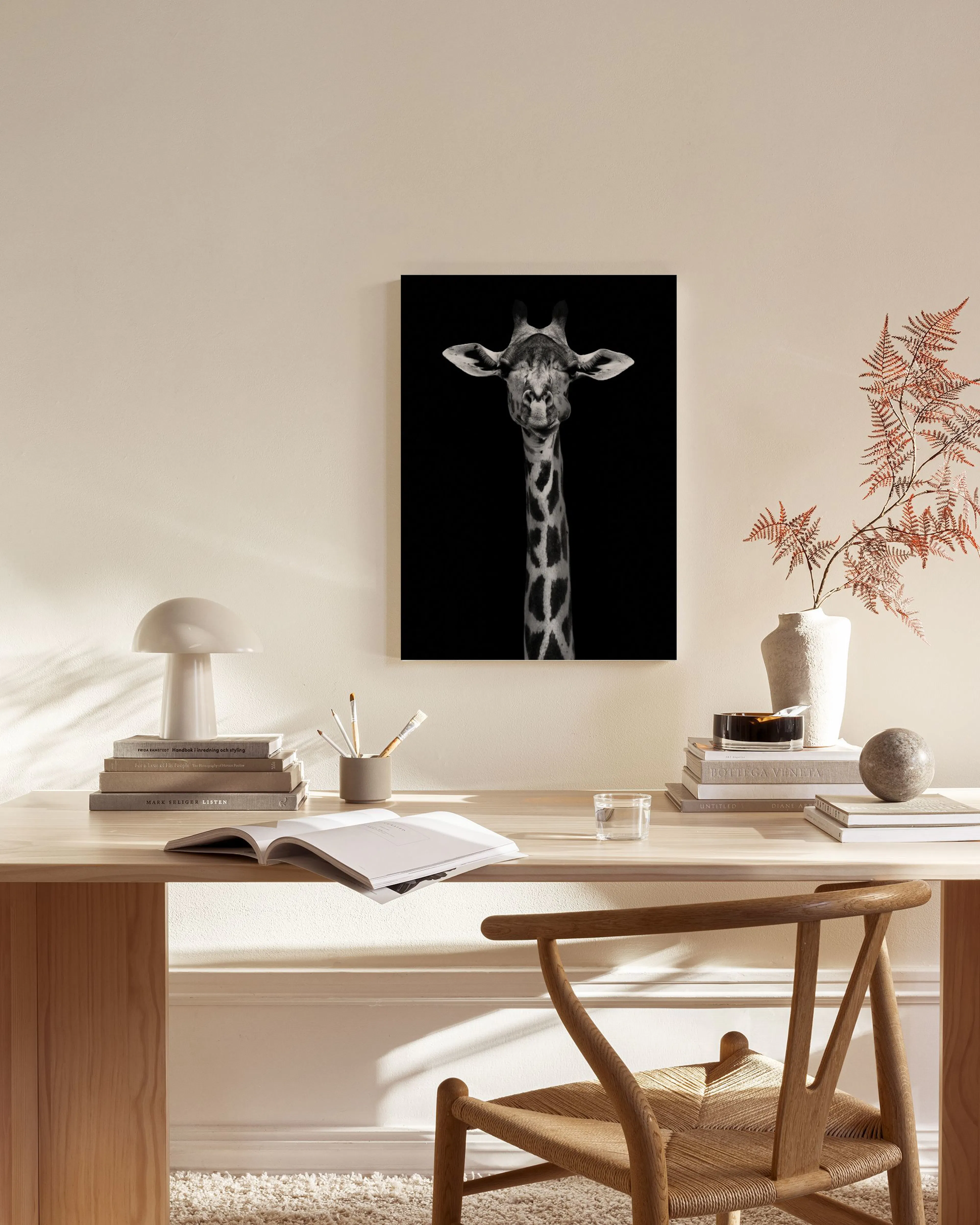 Black and white canvas print of a giraffes head and neck on a black background, hanging in a minimalist living room.
