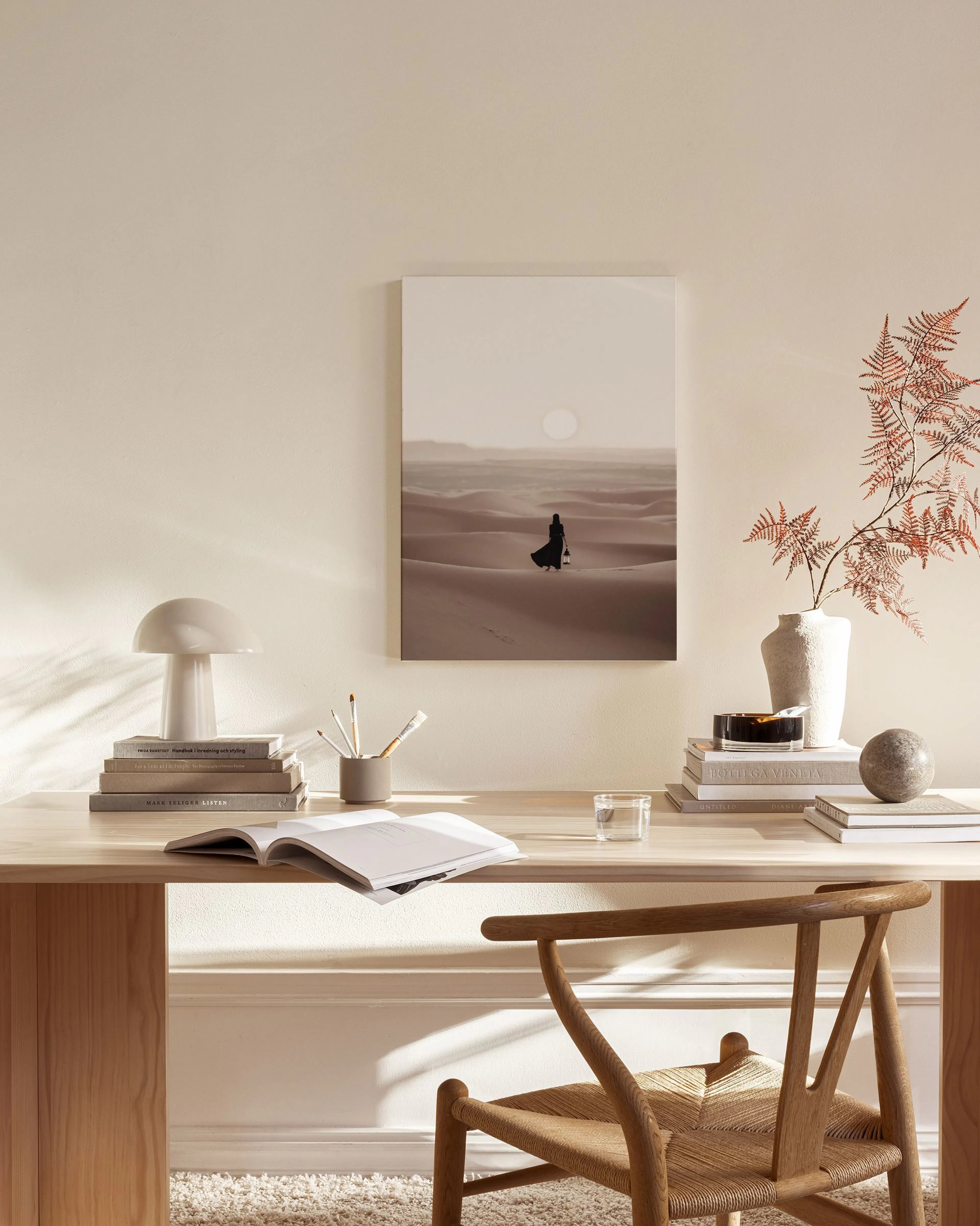 Leinwandbild einer Person mit Laterne in der Wüste, über einem Sideboard in einem beigefarbenen Raum.