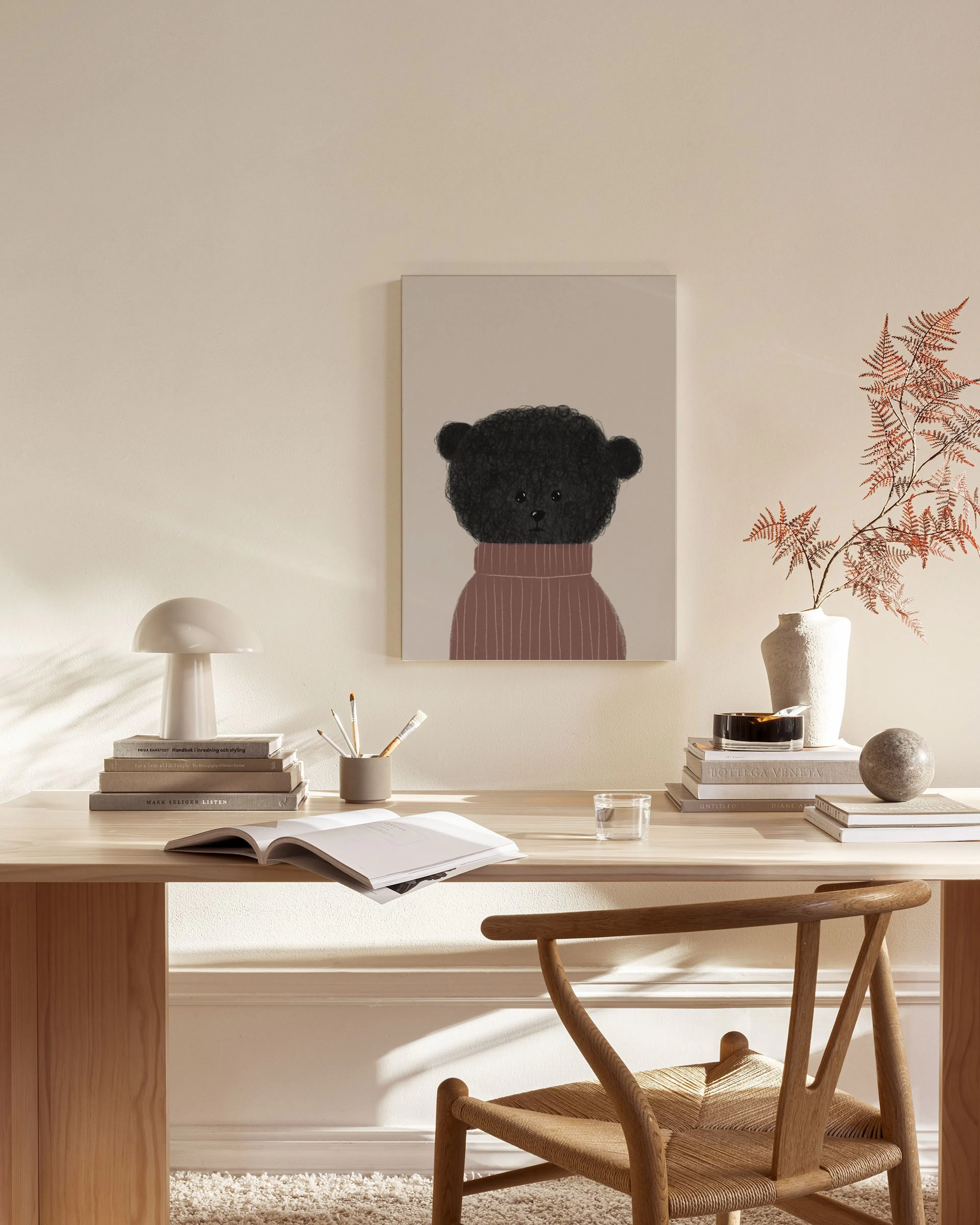 A canvas print of a cute black fluffy bear wearing a reddish-brown sweater, hanging in a minimalist living room.