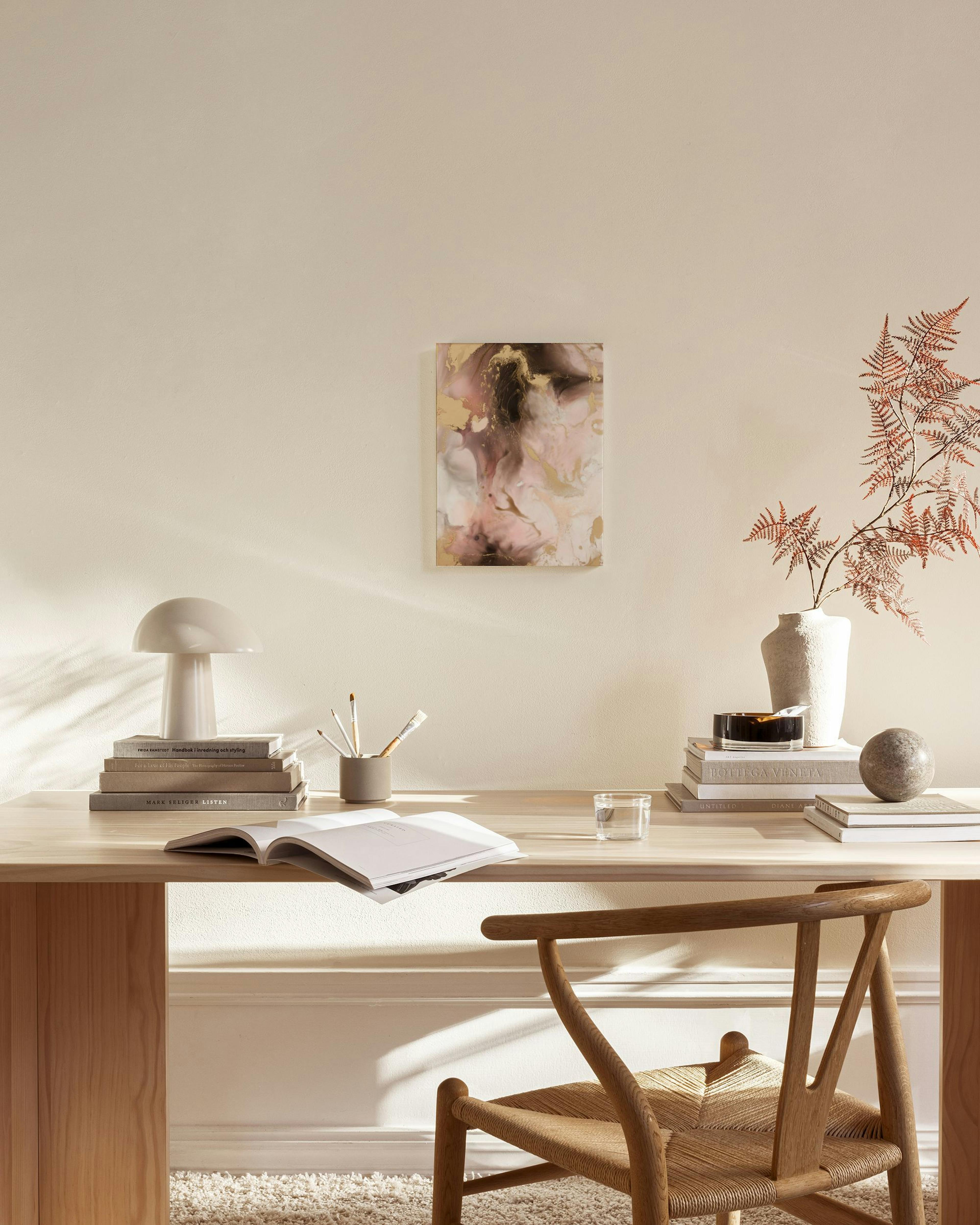 Abstract canvas print with swirling pink, black, and gold colors, hanging above a console table in a neutral living room.