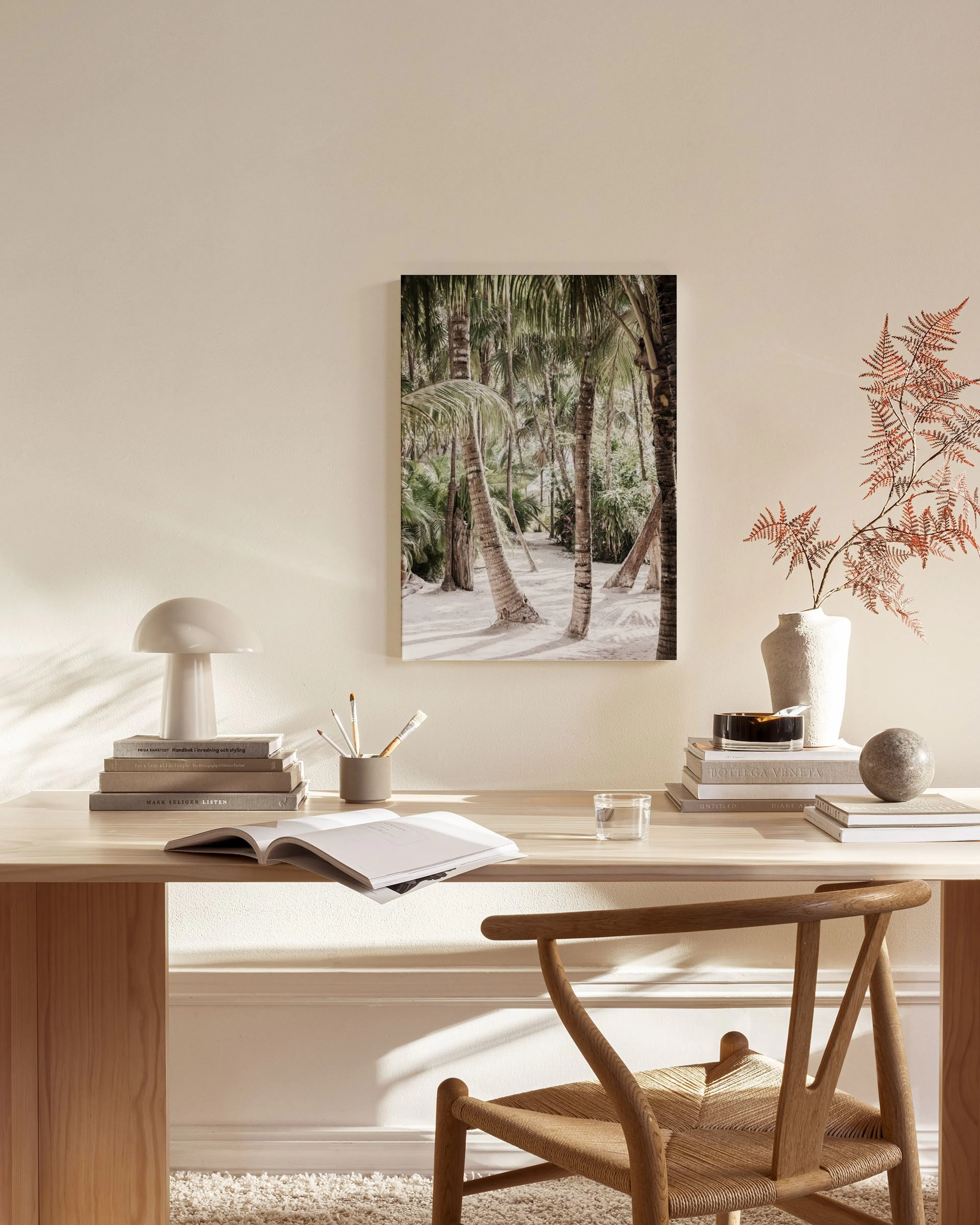 A tropical canvas print of palm trees on a sandy beach, hanging above a wooden media console in a living room.