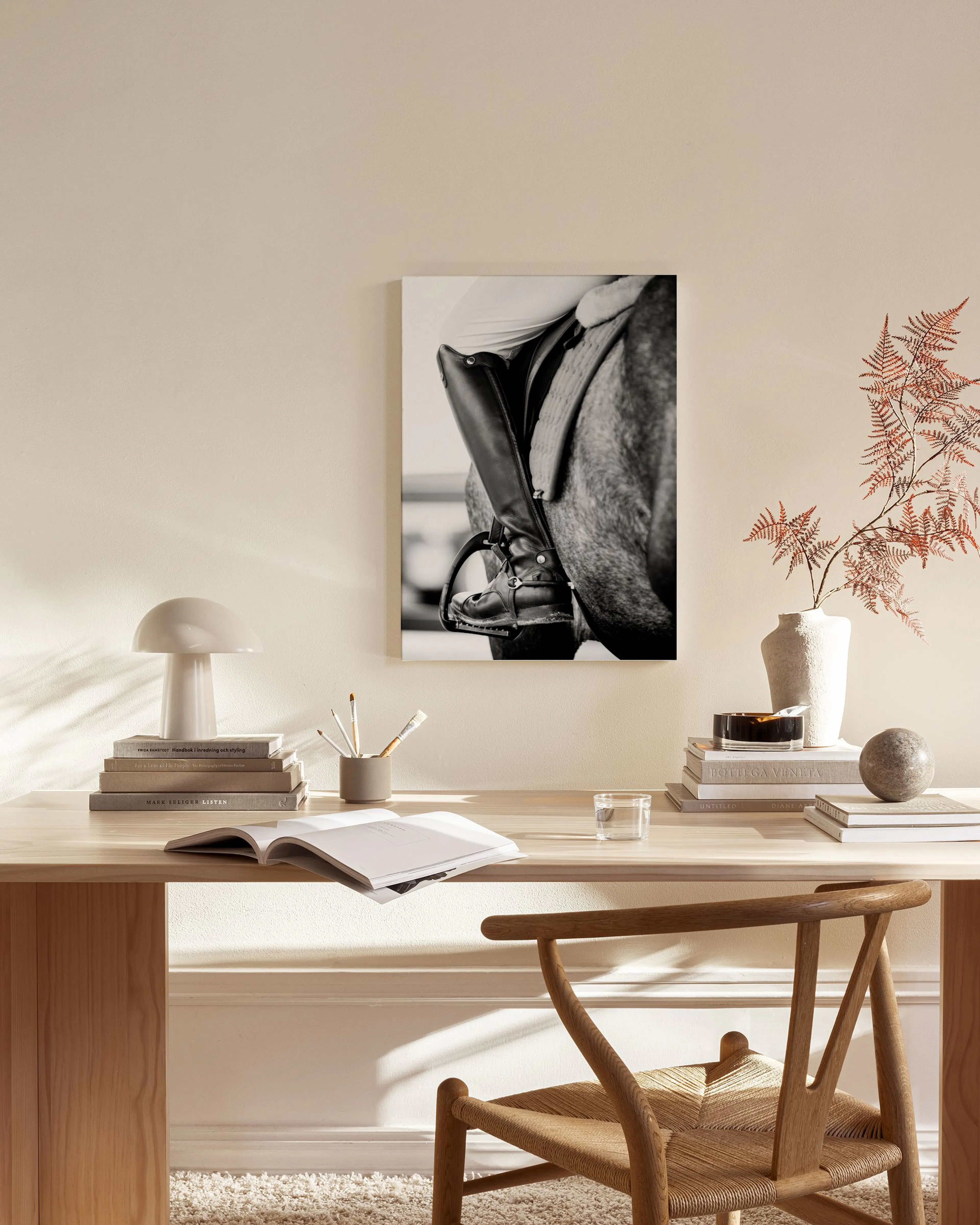 Leinwandbild einer Reiterstiefelette am Pferd in Schwarz-Weiß, hängend über einem Sideboard im Wohnzimmer.