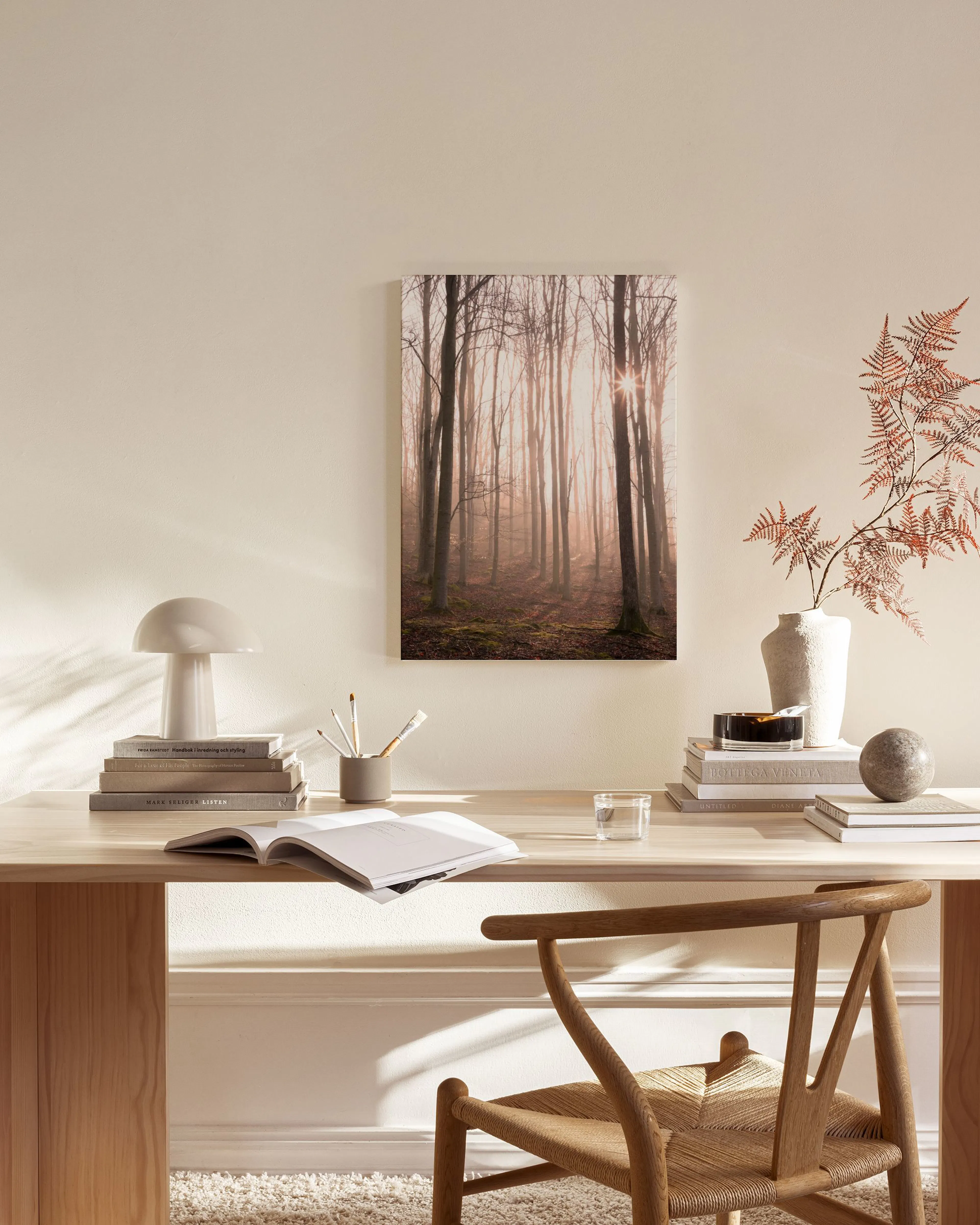 Toile de forêt brumeuse avec un soleil éclatant, accrochée dans un salon moderne aux tons neutres.