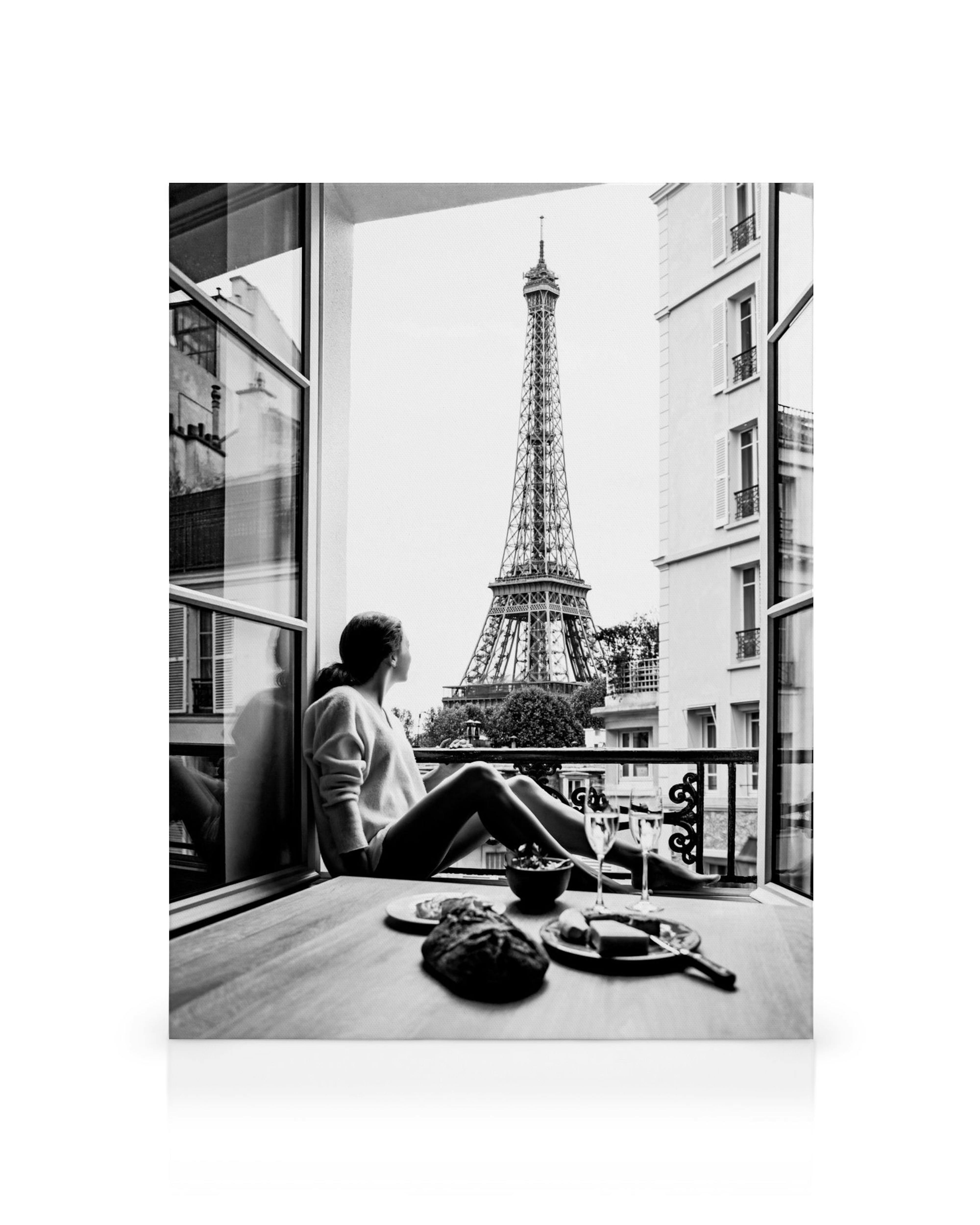 Zwart-wit canvas van een vrouw die vanuit een open raam uitkijkt op de Eiffeltoren in Parijs