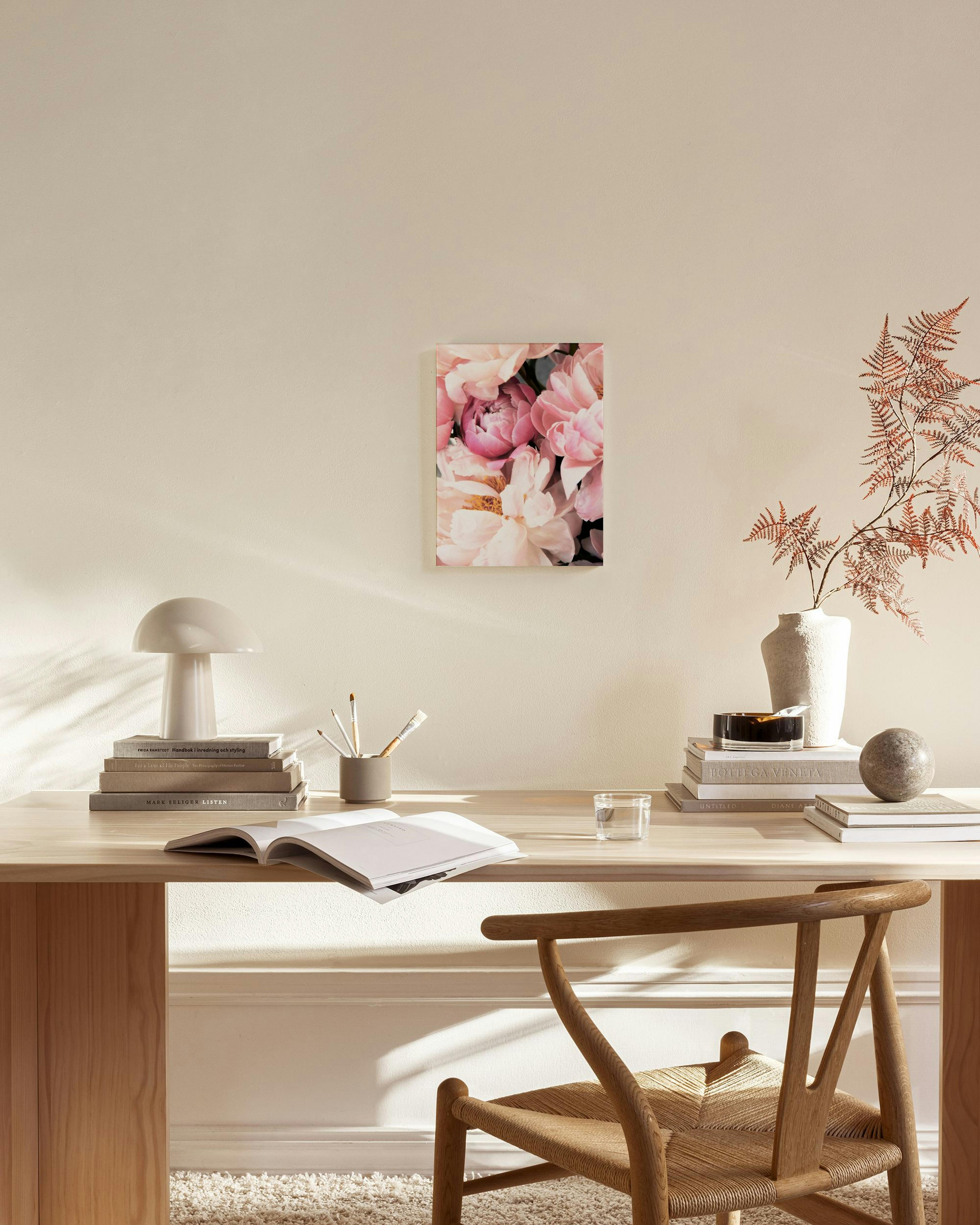 A canvas print of vibrant pink and cream peonies, hanging above a wooden media unit in a bright, minimalist living room.