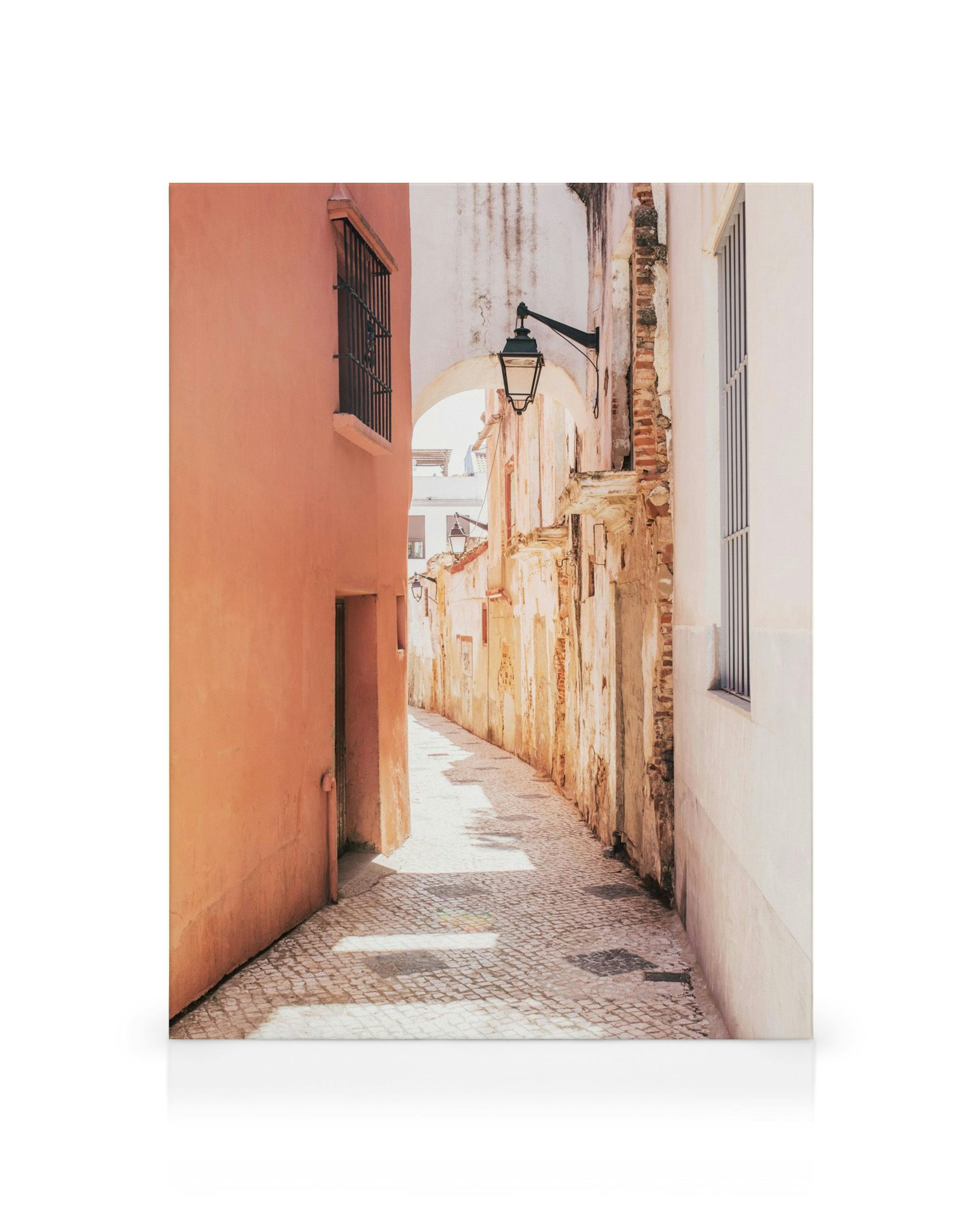 Spanish Alley canvas print features a narrow, cobbled alleyway with warm-toned buildings and an old street lamp.