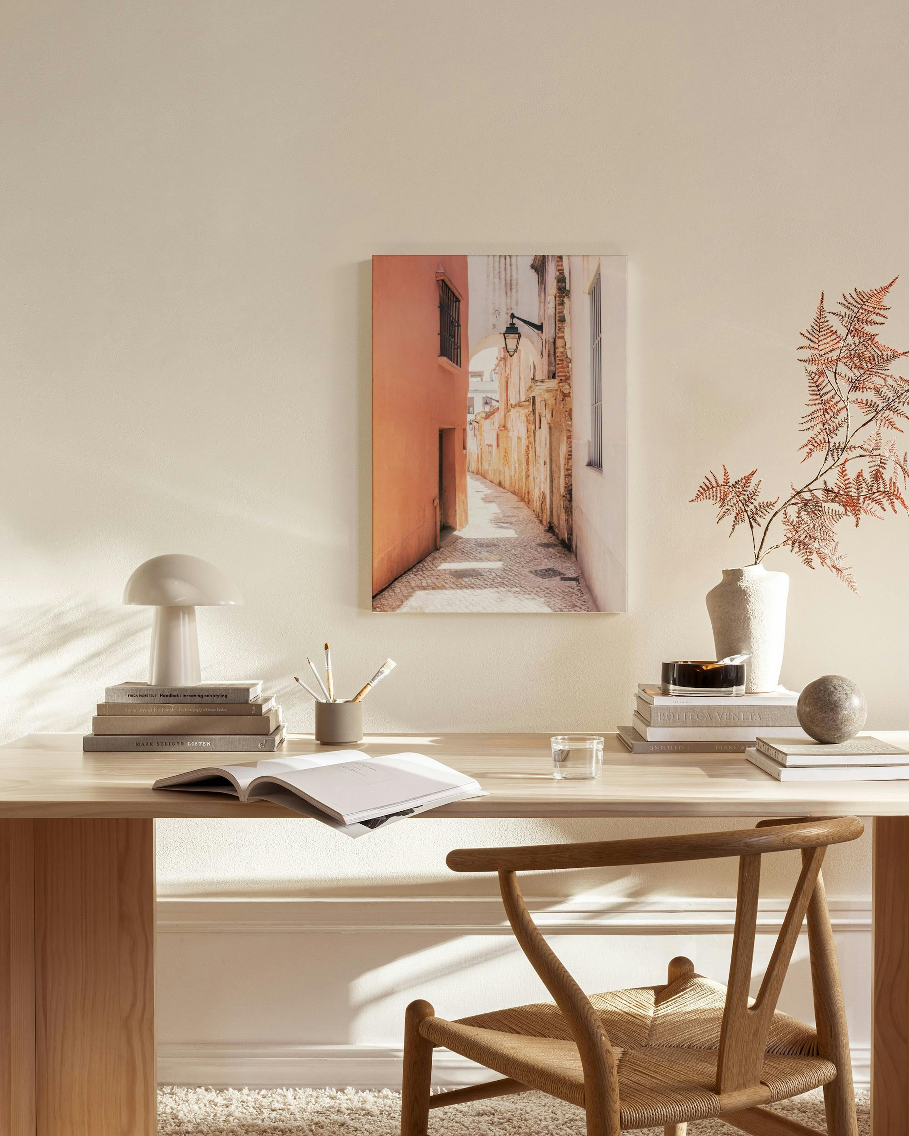 Obraz na plátne zobrazuje úzku, dláždenú uličku s vysokými stenami v ružovom a béžovom odtieni, visiacu v obývačke.