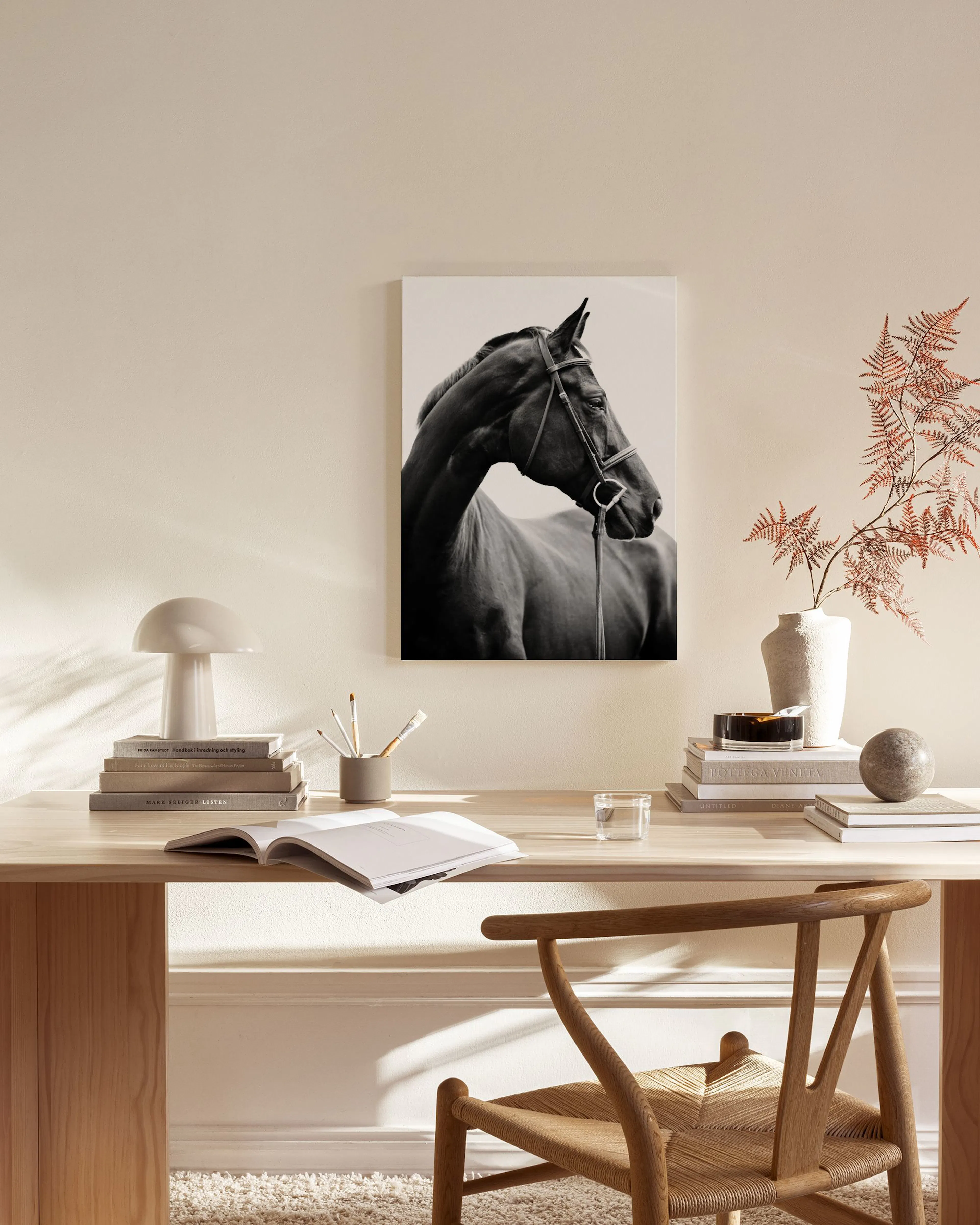 Black and white canvas print of a horse wearing a bridle, hanging in a bright, modern living room.