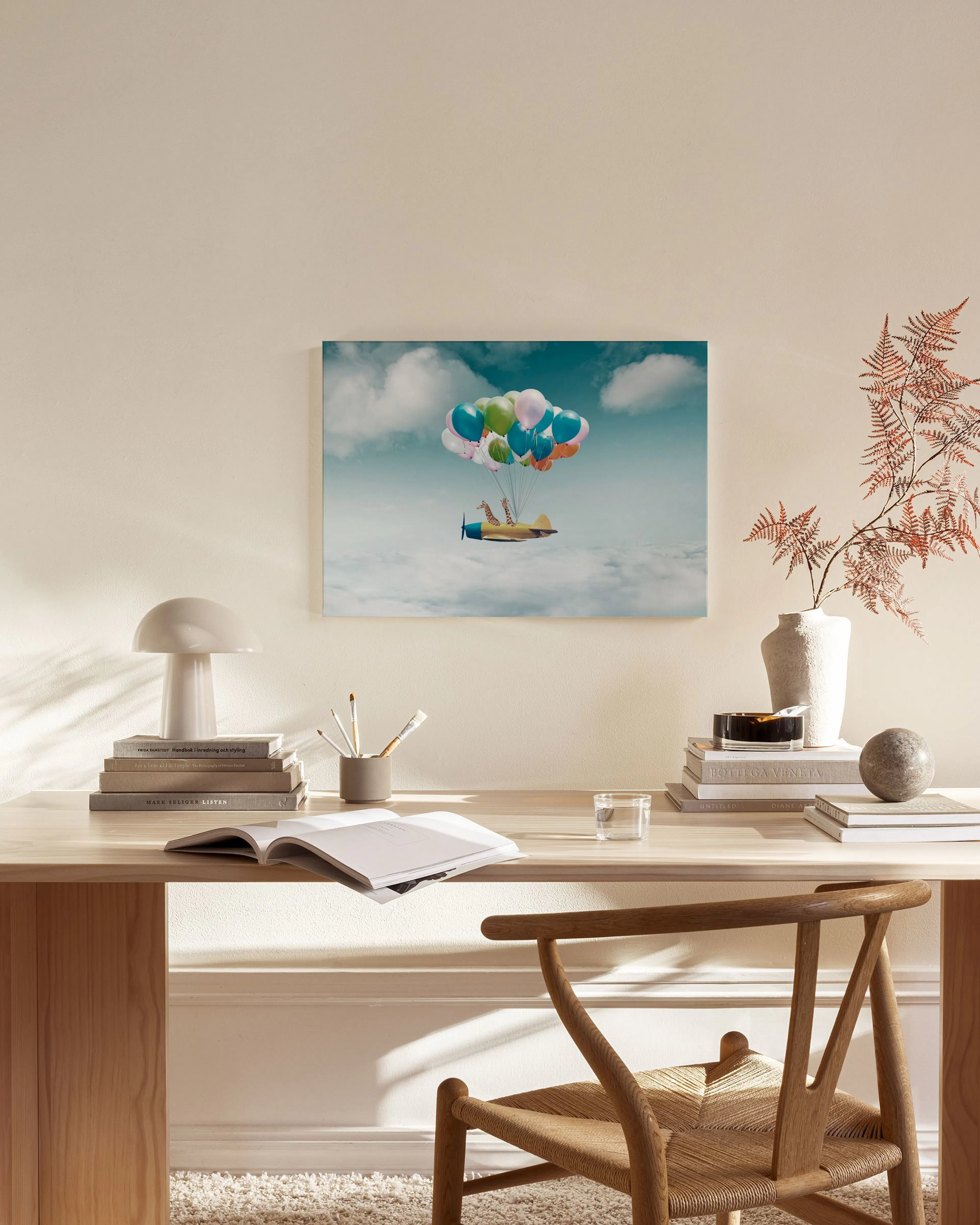 A canvas print of a toy airplane with balloons flying through clouds, displayed in a modern living room.
