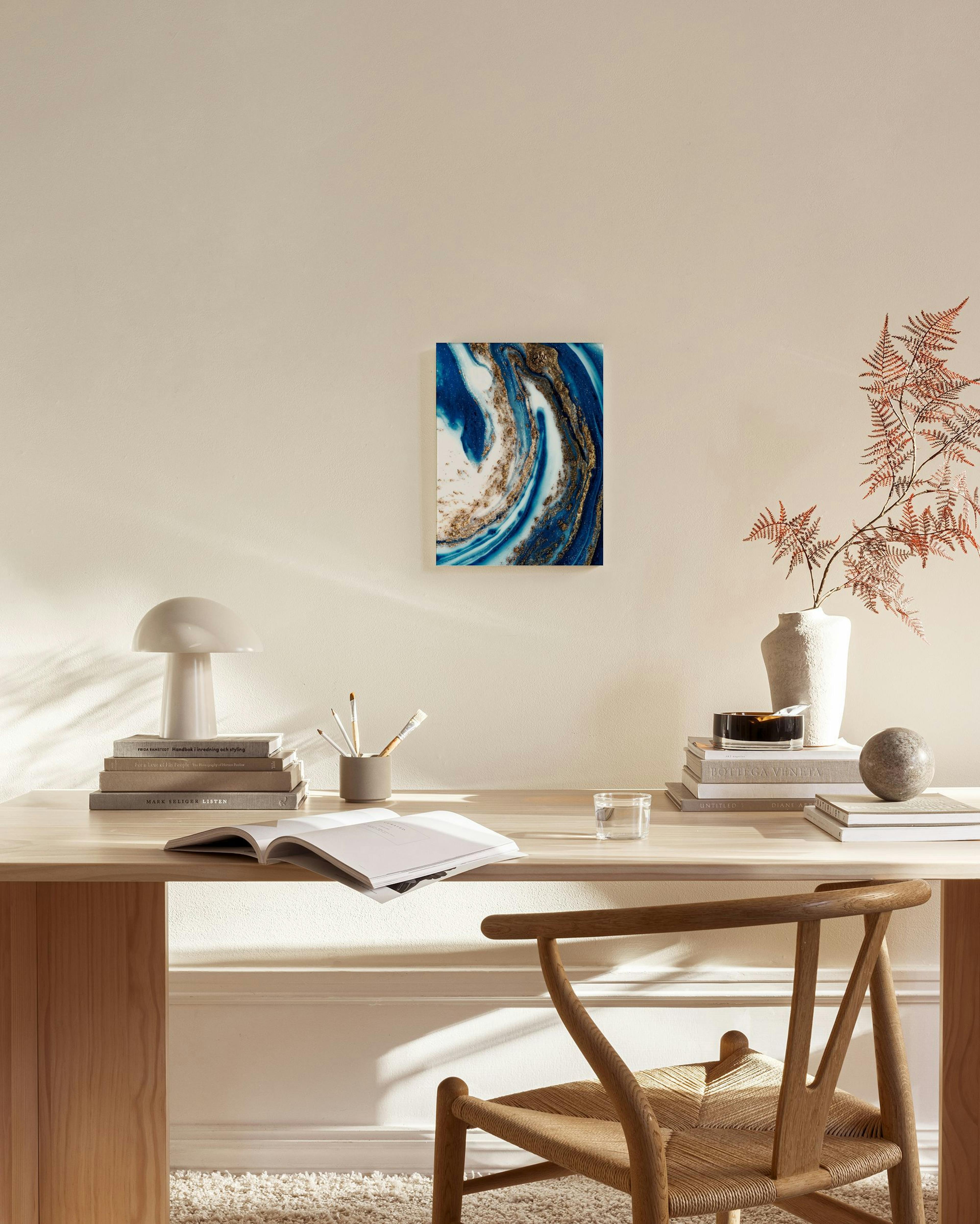 Obraz na płótnie z abstrakcyjnym wzorem w odcieniach błękitu, bieli i złotych smug, zawieszony w jasnym salonie.