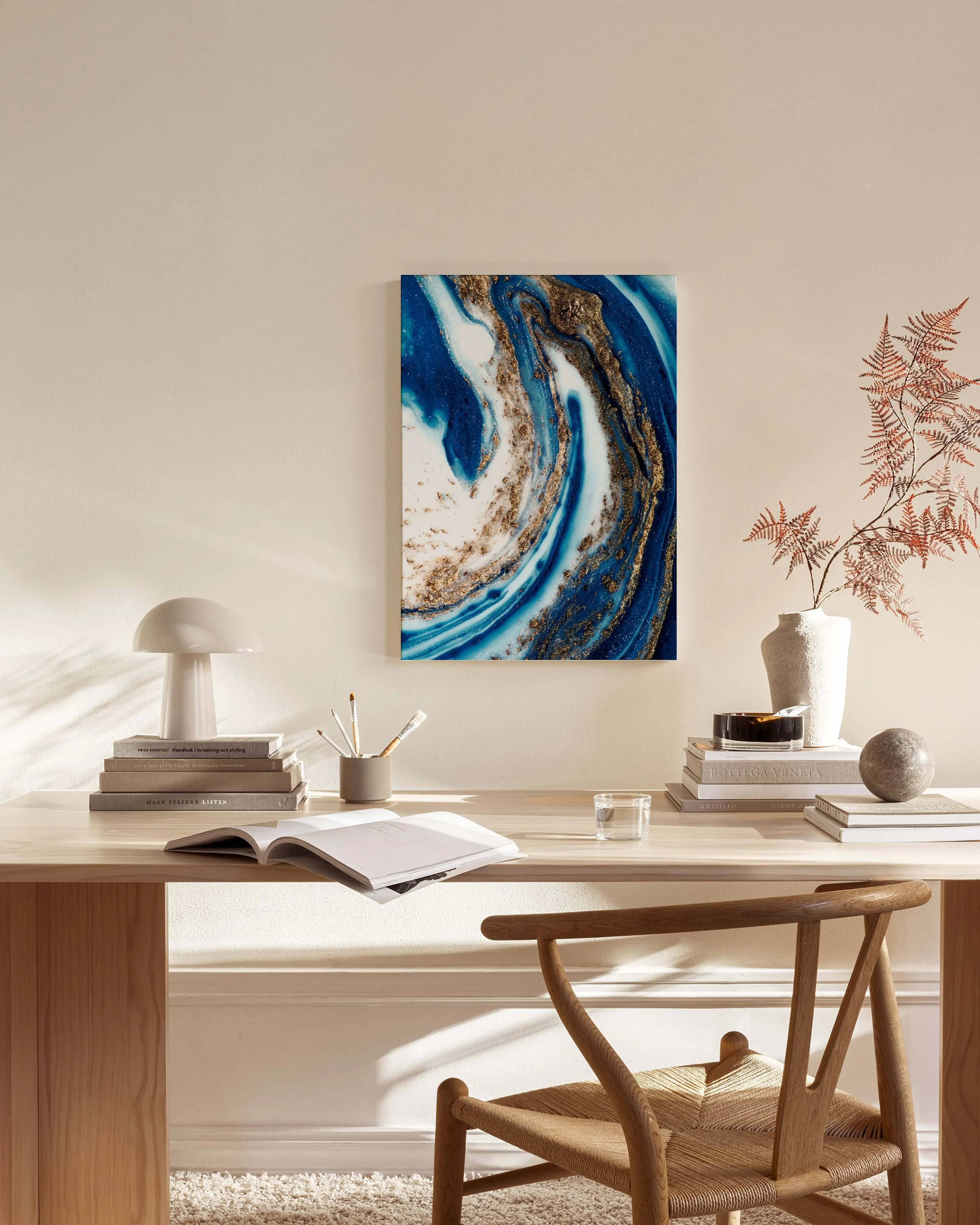 Canvas met blauwe, witte en goudkleurige wervelingen, hangend in een neutrale woonkamer boven een dressoir.