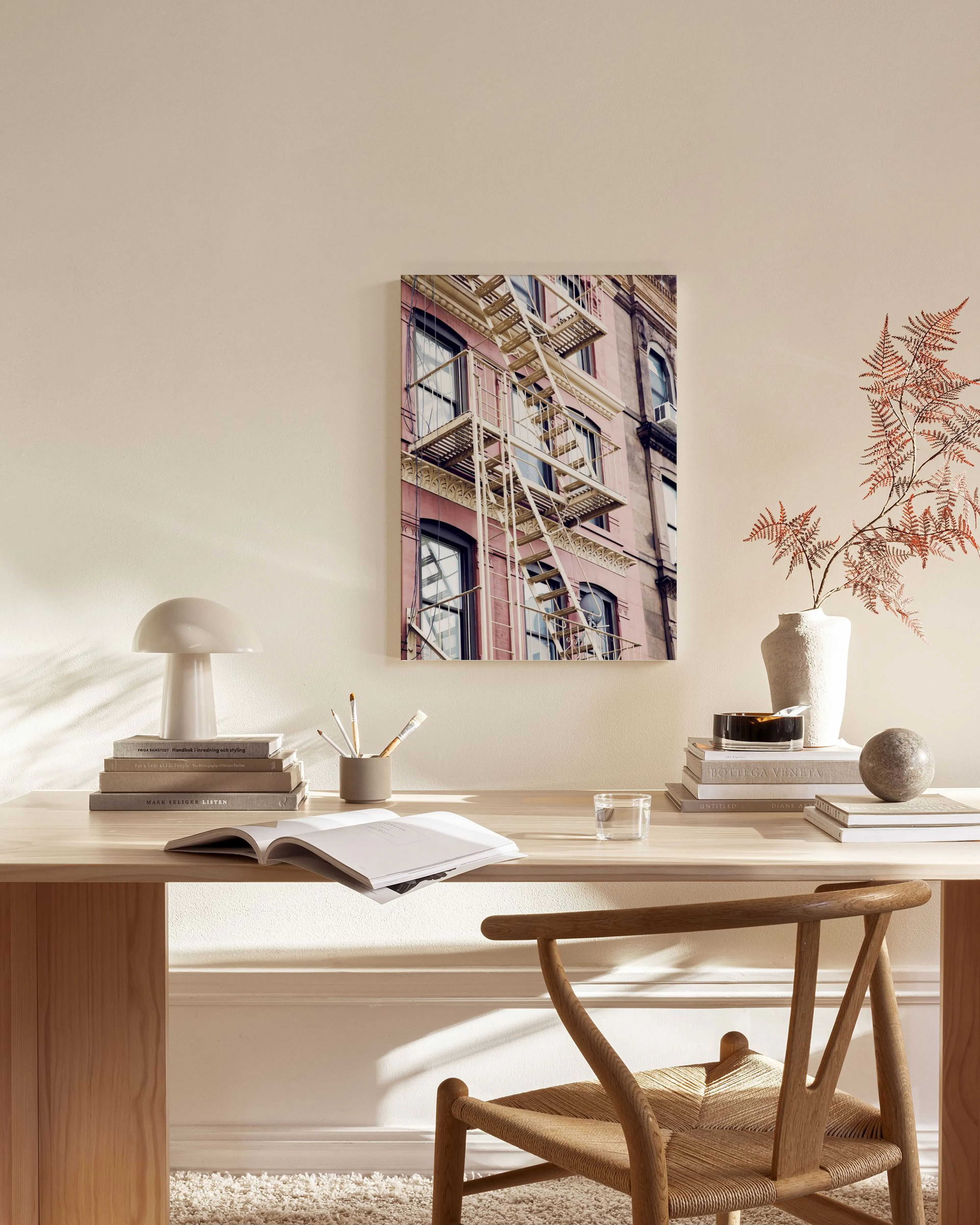 Canvas van een roze gebouw in New York met brandtrap, hangend in een modern interieur boven een houten dressoir.