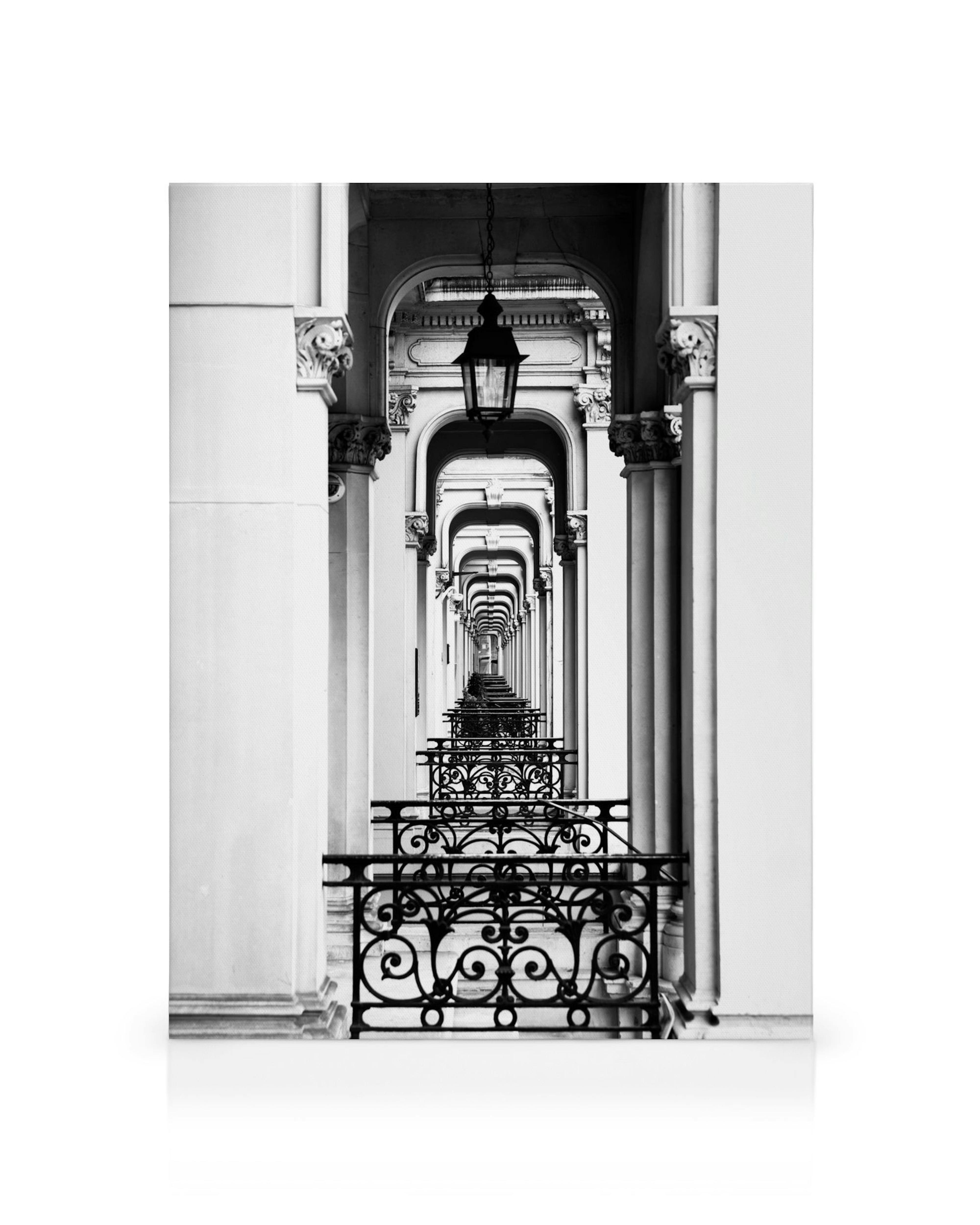 Toile noire et blanche dune architecture historique avec un couloir darcs, de colonnes, de rampes en fer forgé et une lanterne s