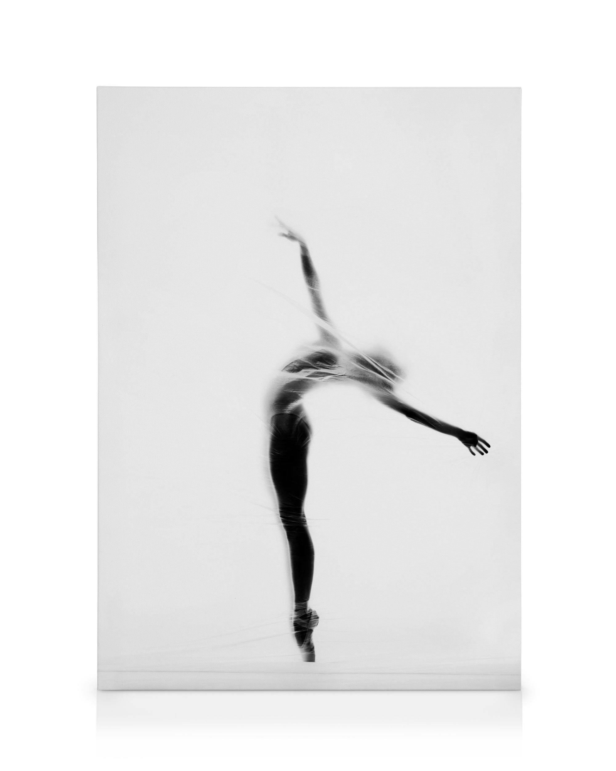 Leinwandbild mit einer Balletttänzerin in Schwarz-Weiss, die elegant auf Spitzenschuhen tanzt. Ihr Körper ist in Bewegung, von e