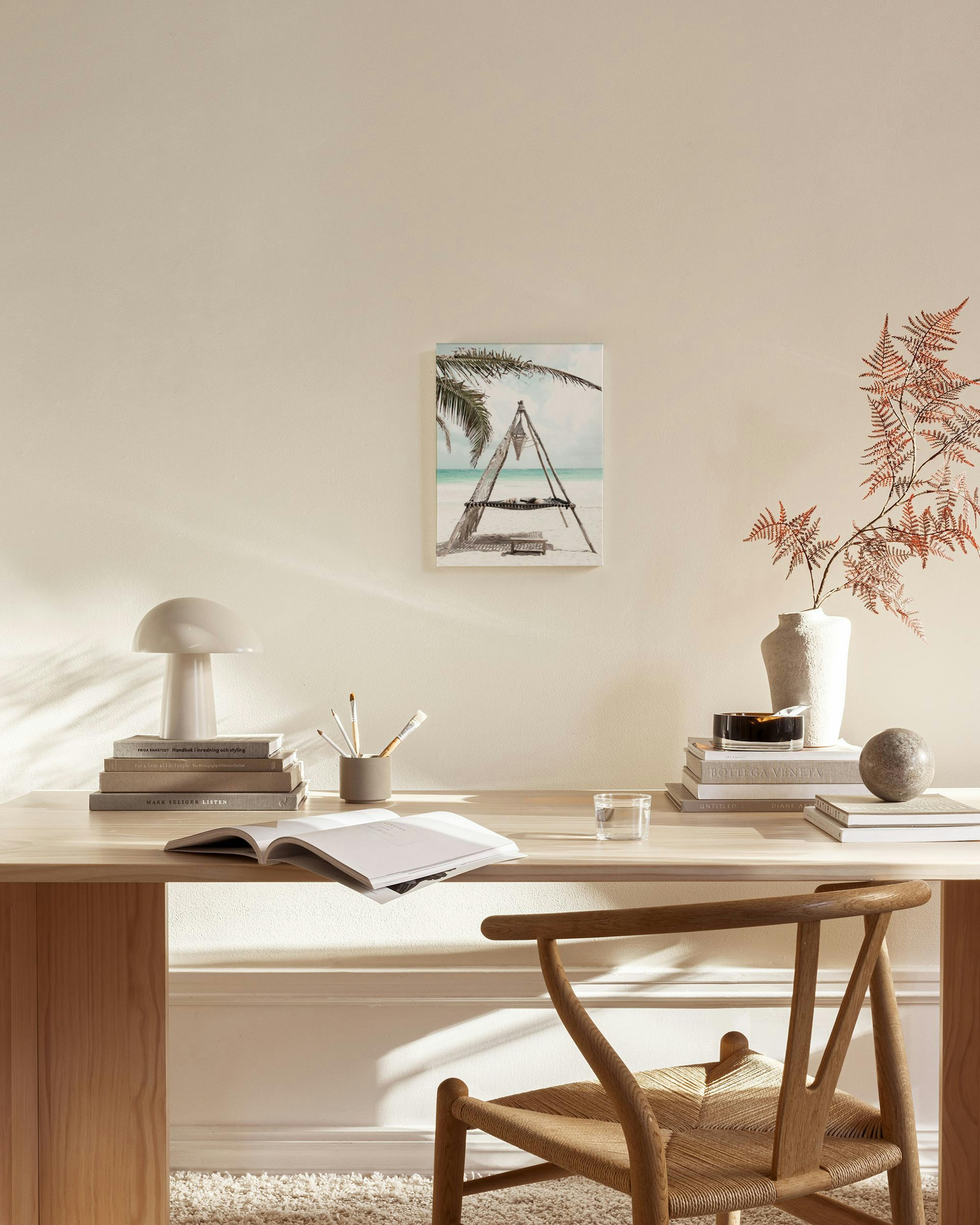 A canvas print of a tropical beach scene with a palm tree, white sand, and turquoise water, displayed in a bright living room.
