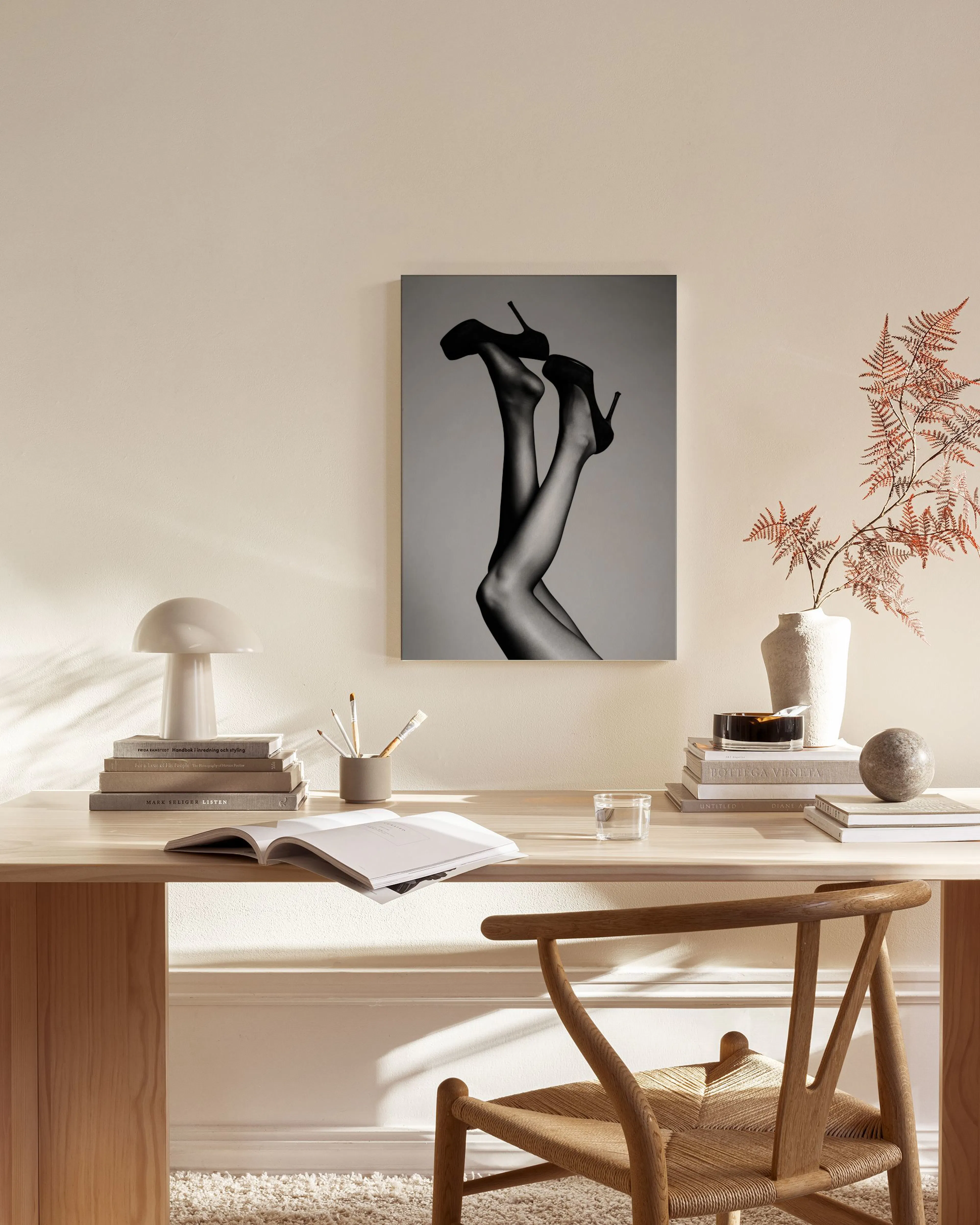 Monochrome canvas print of a womans legs in high heels, hanging in a minimalist living room.
