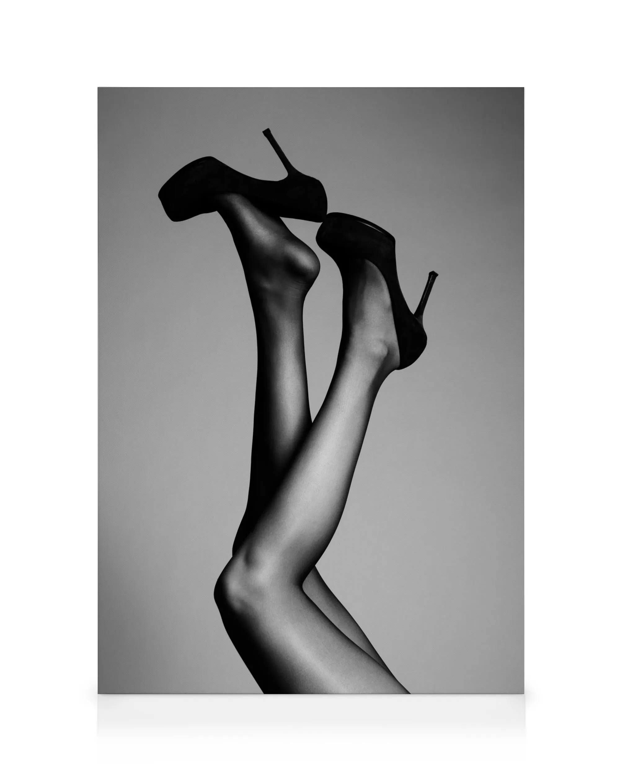 Black and white photograph of a womans legs in pantyhose and high heels, playfully tossed in the air.